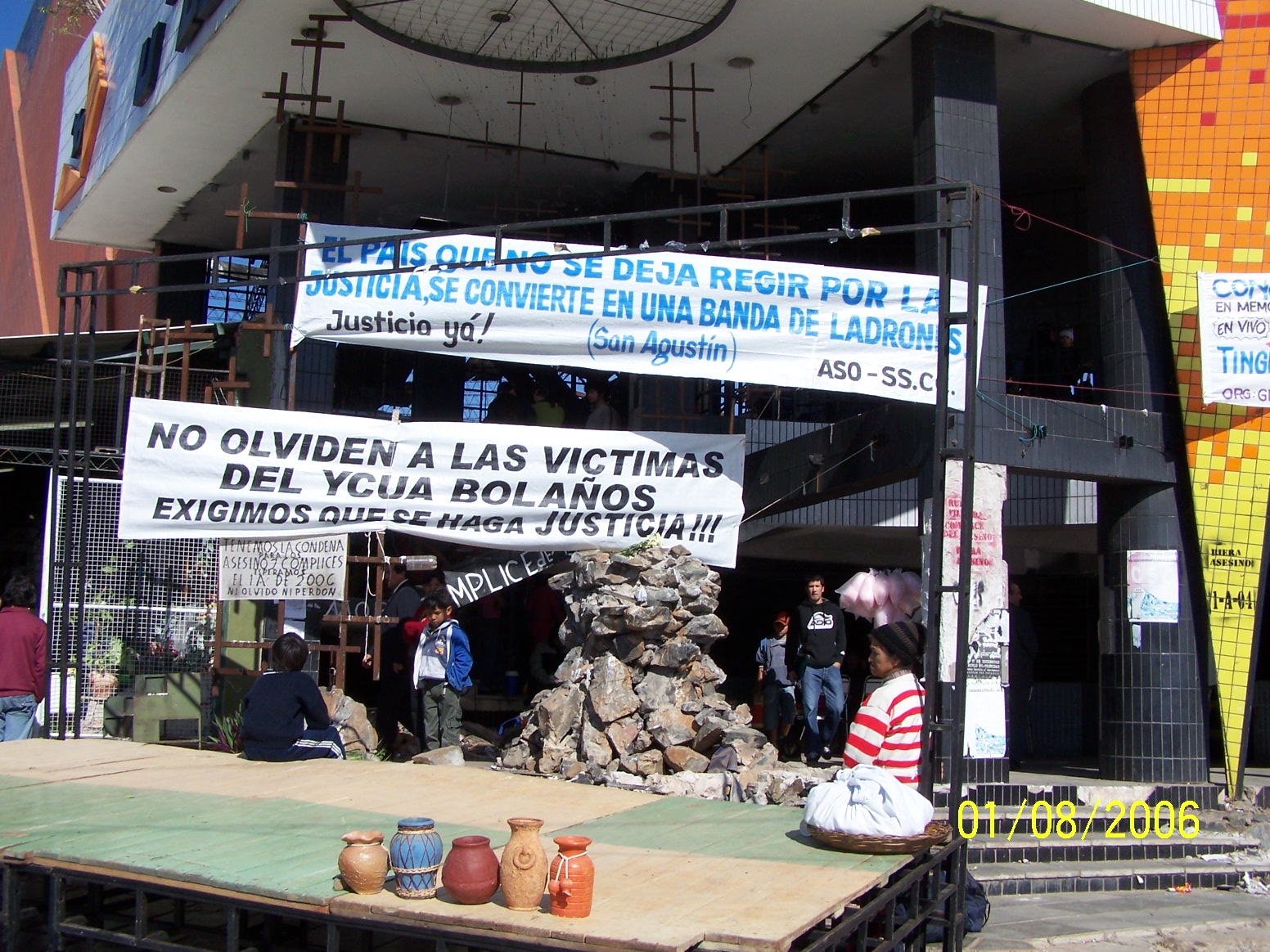 Main entrance of the Ycuá Bolaños V supermarket. Located between General Artigas avenue and Santisima Trinidad avenue of the Trinidad neighborhood in Asunción, Paraguay where on August 1st 2004, 396 people died due to the doors being closed.
In the picture banners of repudiation can be seen asking for justice, alongside a stage mounted for the commemoration of the first anniversary of the fire (01-08-2006).
