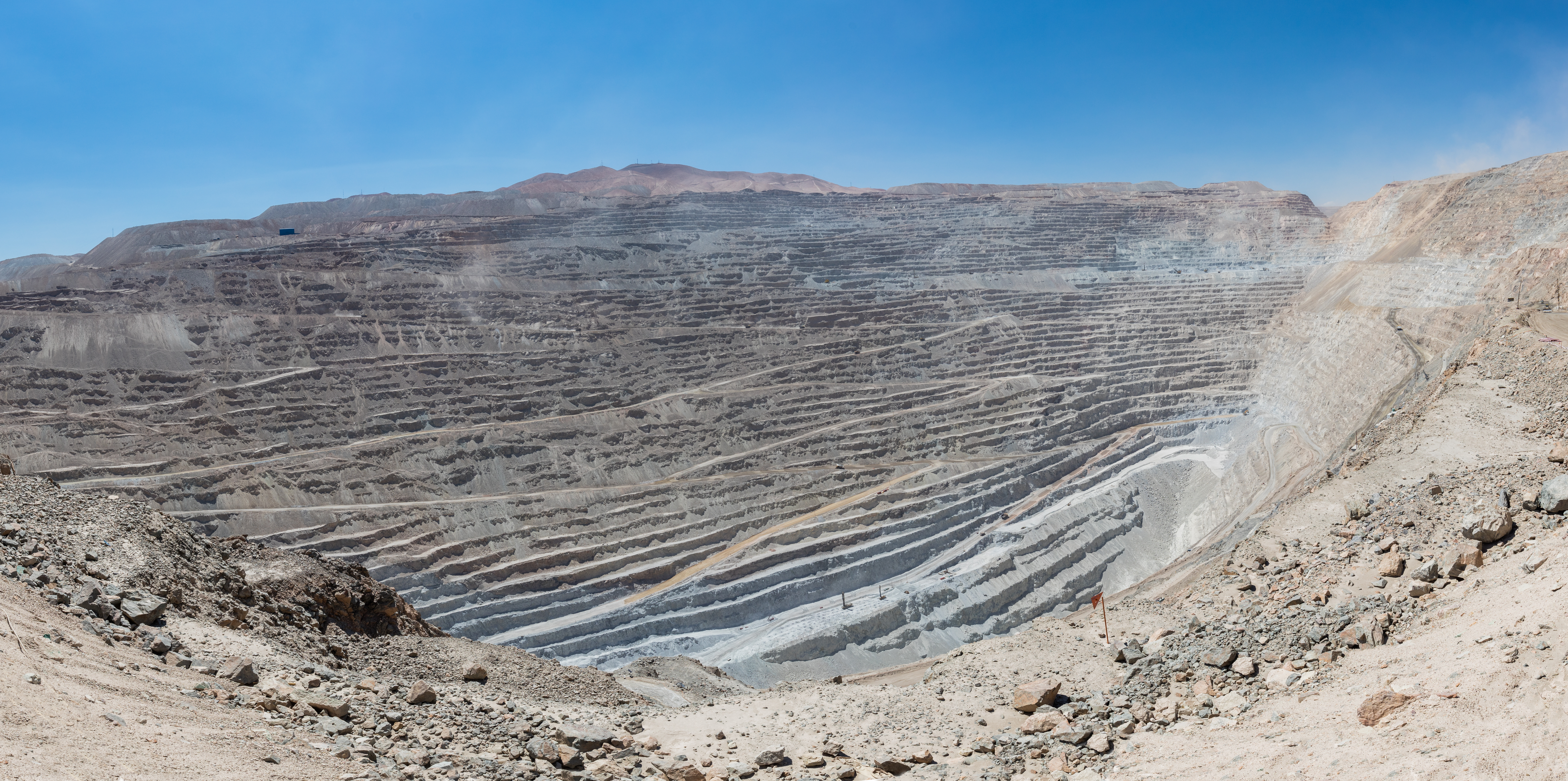 Panoramic view of Chuquicamata, a state-owned copper mine located at 2,850 metres (9,350 ft) above sea level just outside Calama, north of Chile. It is by excavated volume the largest open pit copper mine in the world. The huge hole was started in 1882 as a mine to extract gold and copper. It is 4.5 kilometres (2.8 mi) long, 3.5 kilometres (2.2 mi) wide and with a depth of 850 metres (2,790 ft) it is the second deepest open-pit mine in the world (after Bingham Canyon Mine in Utah, USA). Note: to get a feeling of the scale spot out a haul truck, which is 9.5 metres (31 ft) long and 4.5 metres (15 ft) high.