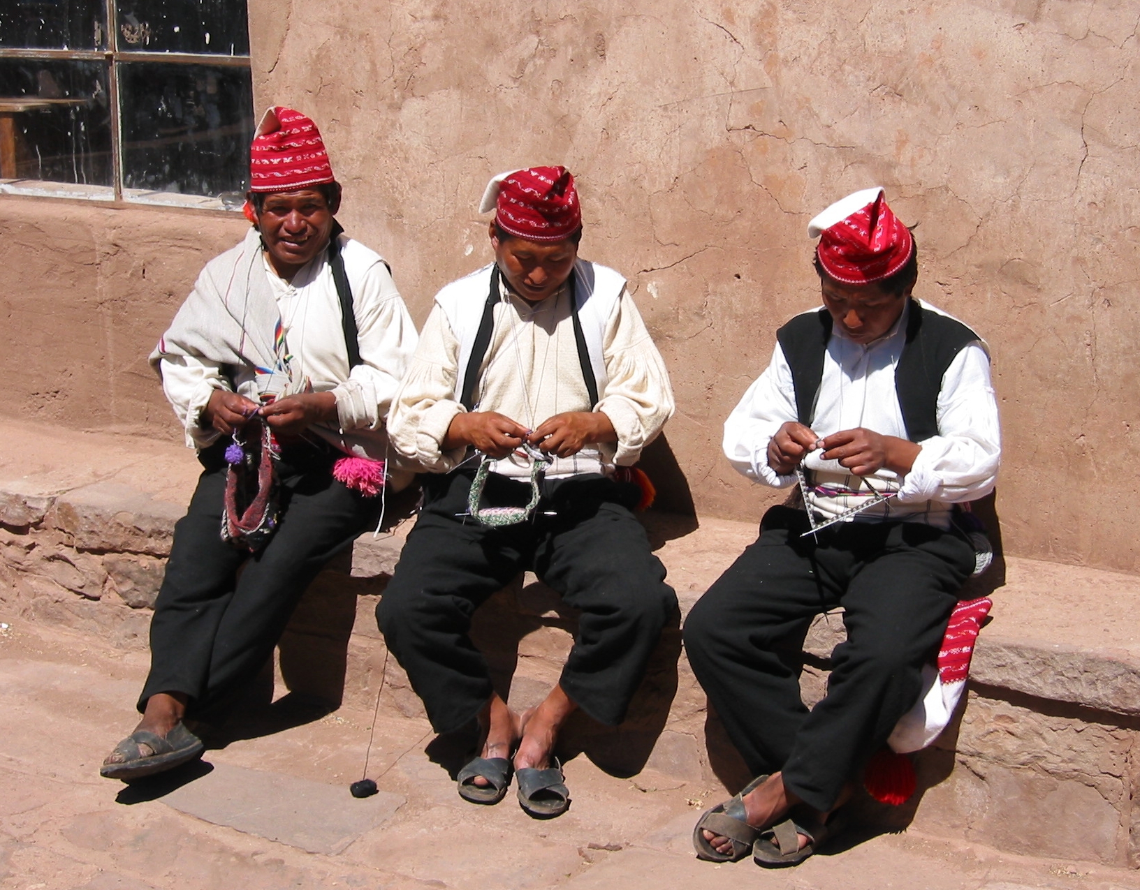 Three men knitting on the Island of Taquile, Lake Titicaca, Peru.  The island is known for its textile goods.