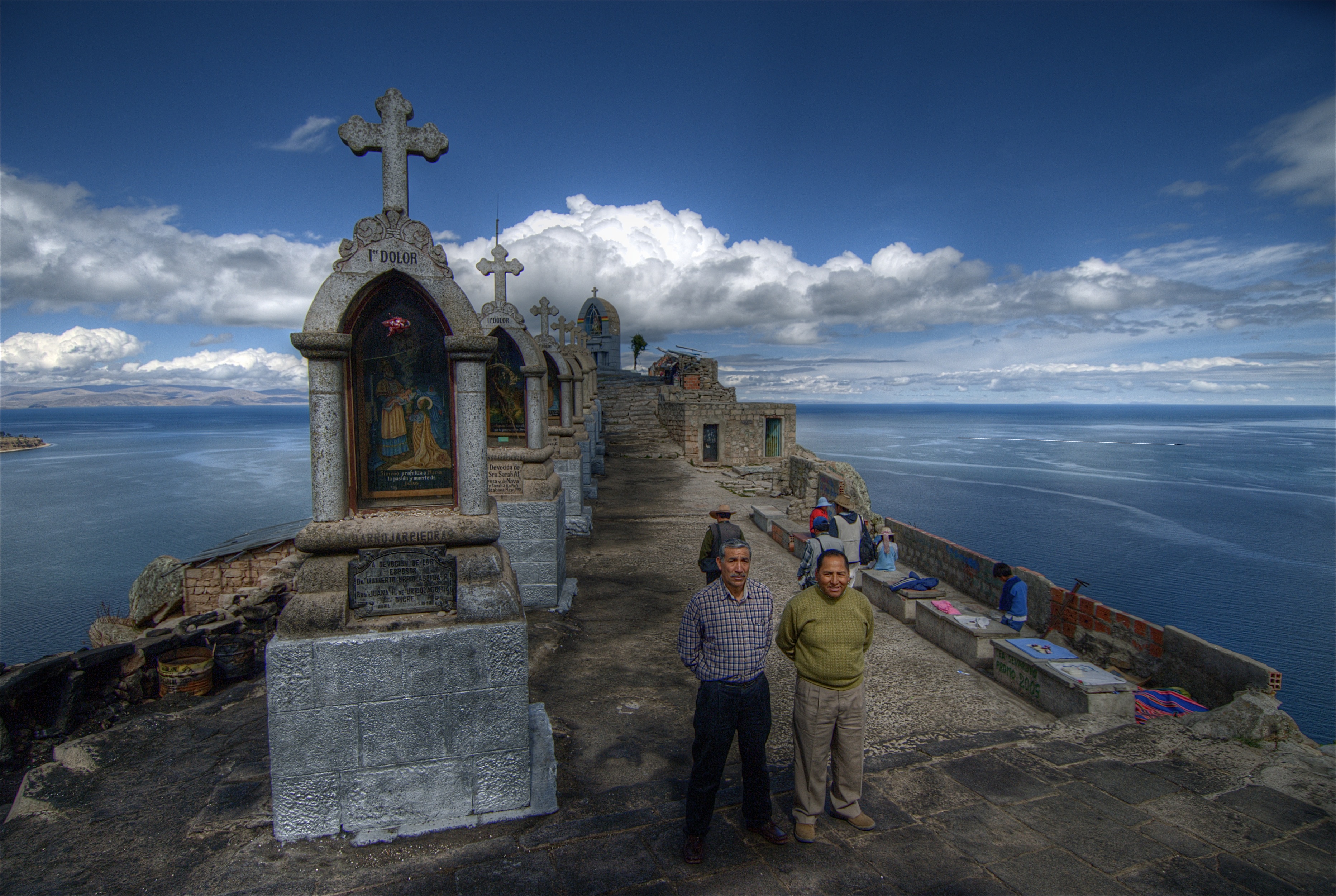 Local men standing on the hill overlooking the town of Copacabana on the shores of Lake Titicaca in Bolivia. The hilltop was a shrine where the locals came to light candles, make offerings, and buy small amulets. October 2007.