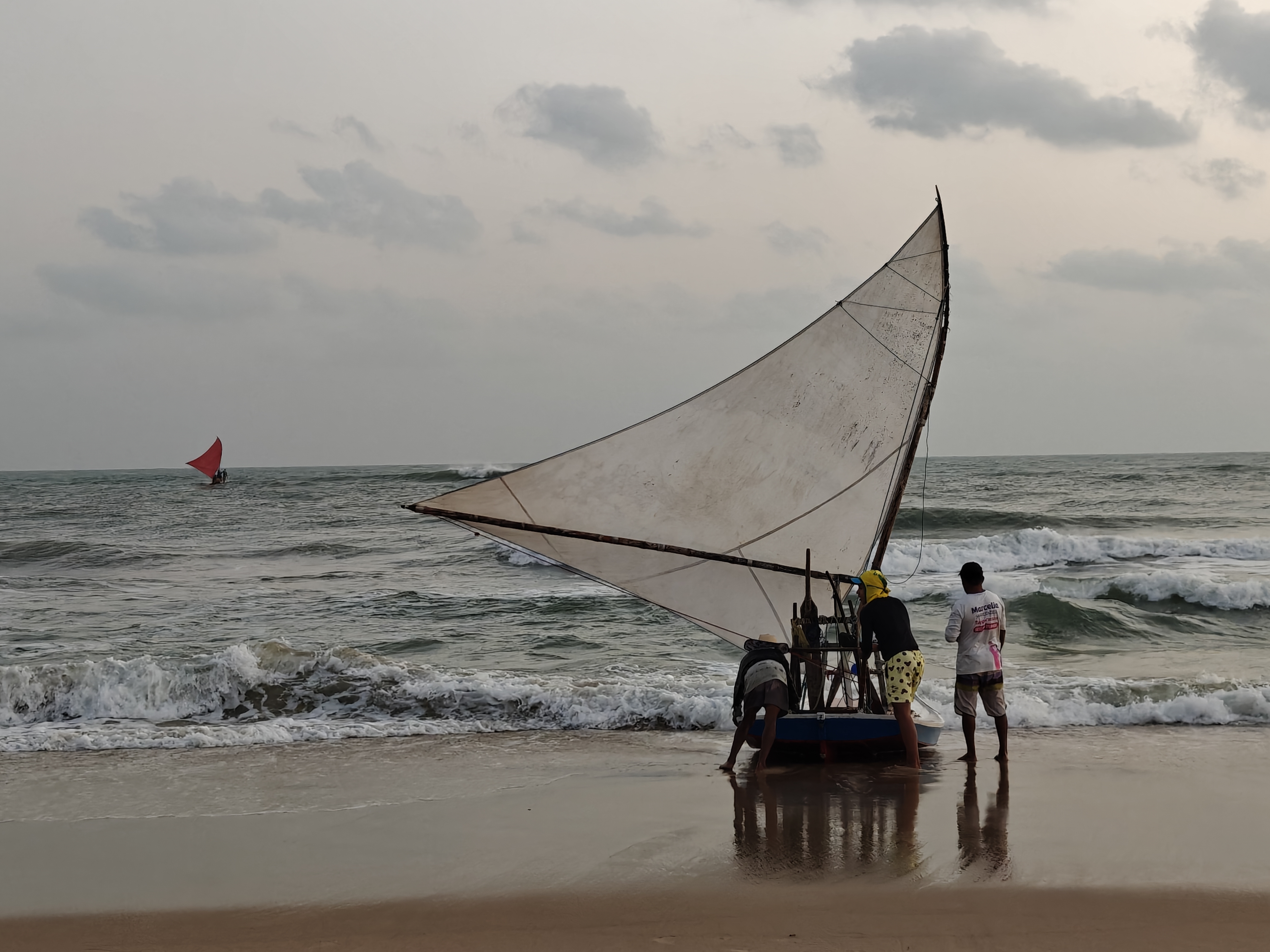 Three fishermen are ready to push their traditional jangada into the waves to go on a fishing expedition at sunrise. Another one has just left.