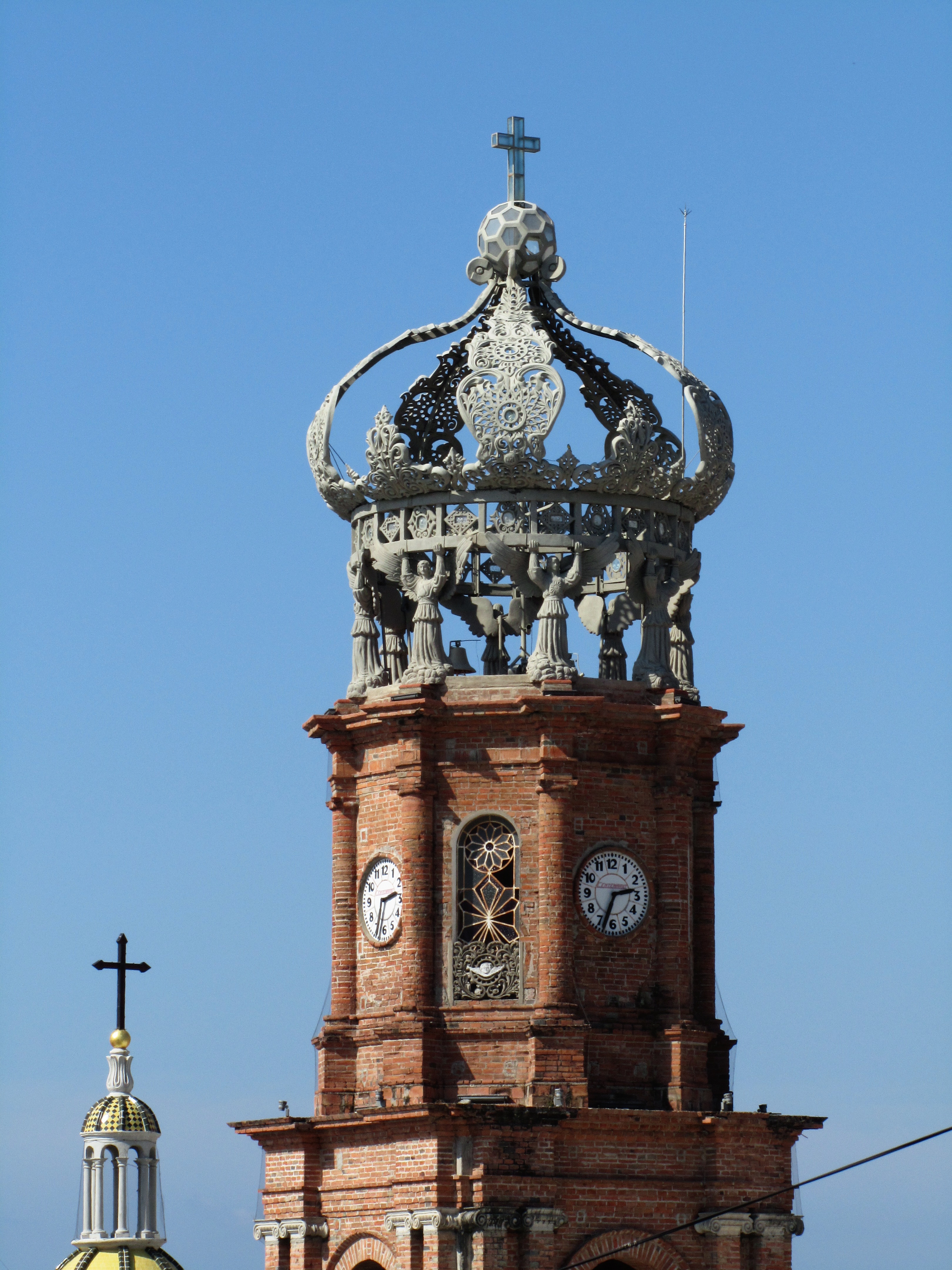The Crown of Our Lady of Guadalupe Cathedral — Puerto Vallarta, Jalisco state, México. 
Author: Sculptor and painter Carlos Terres.
10.00 m in diameter and 15.50 m in height; sculpture in terroca (terres stone).
The master sculptor and painter Carlos Terres made The Crown of Our Lady of Guadalupe basing his monumental sculpture in Nahuatl world Tecuntlanopeuh which means "that which has its origin at the peak of the boulders", alluding to the original name of the port, presently known as Puerto Vallarta.
Symbolic elements of the sculpture are as follows. Eight angles wearing Marian symbols on their breast are holding the crown. The gems of the ring represent the 24 hours of the day. The five small palms represent the joyful mysteries of the Marian rosary. The five large palms represent the founding of Puerto Vallarta on December 12, 1851.
Construction of the parish church began on April 15, 1883. The second phase of construction in 1915. The naming of the parish church in 1921. The borders of the sculpture are formed by a world of glass and a cross.
Benediction by Bishop P. Ricardo Waty on October 12, 2009.

Parish church of Our Lady of Guadalupe, Puerto Vallarta, Jal. Mexico.