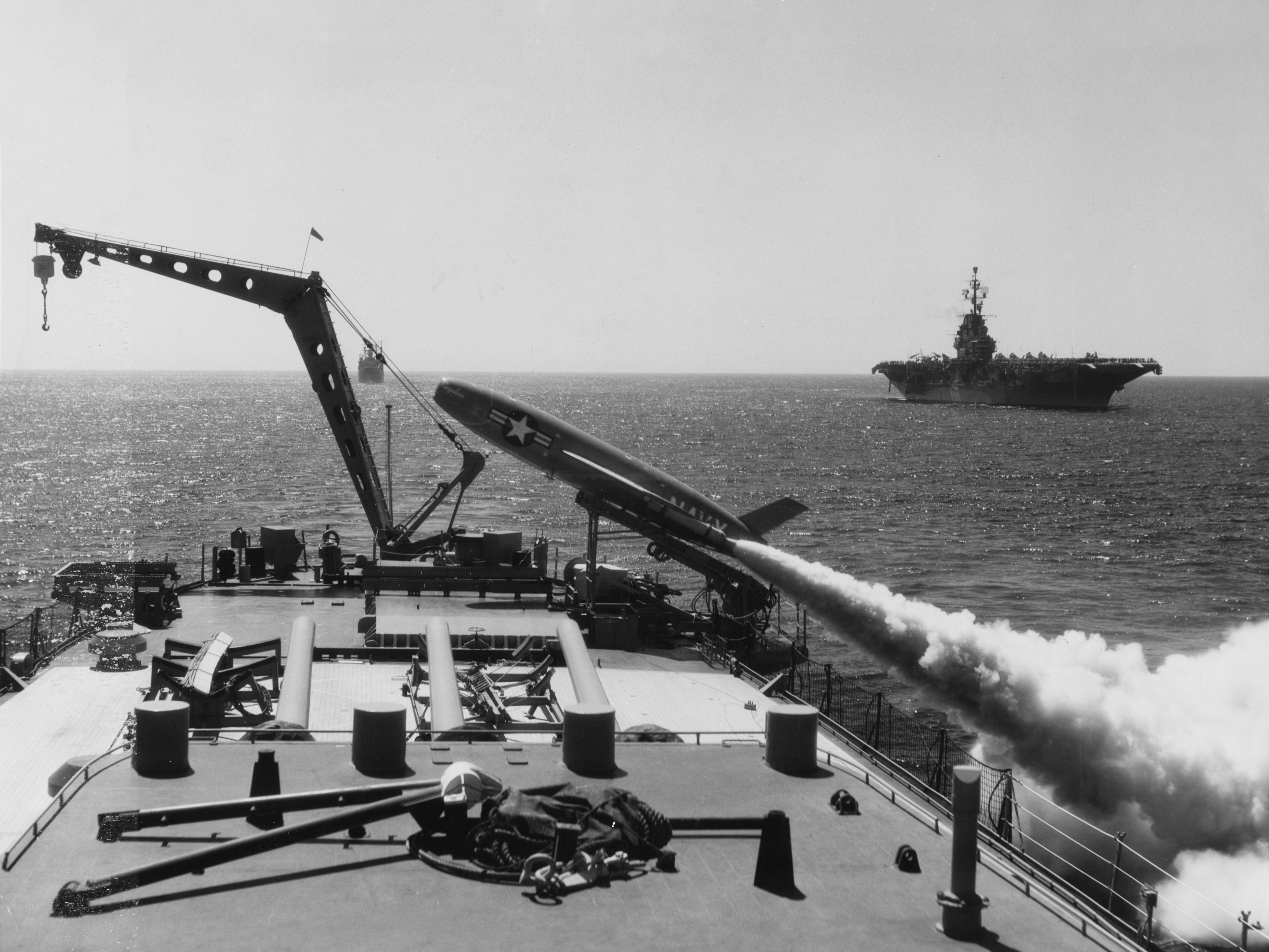 The U.S. Navy heavy cruiser USS Los Angeles (CA-135) firing a SSM-N-8 Regulus I missile, on 7 August 1957. The aircraft carrier USS Ticonderoga (CVA-14) is visible in the right background, the missile test ship USS Norton Sound (AVM-1) is visible behind the crane.
Original caption: "West Coast Cruisers Capable of Nuclear Assault -- A Regulus I boils white smoke from booster charges as it roars away from its launcher aboard the heavy cruiser USS Los Angeles off San Diego. The launch, a routine evaluation 'shoot', was conducted during the time that 600 members of the Institute of Aeronautical Science were embarked aboard the attack carrier USS Ticonderoga (CVA-14), right. The demonstration, which included a 'Terrier' guided missile interception of the Regulus, power exhibition, carrier operations, and a HUK exercise, was highlighted by the Regulus launching. The Terrier was fired at the Regulus from the USS Norton Sound (AVM-1), background, on August 7." (Text quoted from the original photo caption, which was released by Commander, Cruiser-Destroyer Force, U.S. Pacific Fleet, on 9 August 1957.)