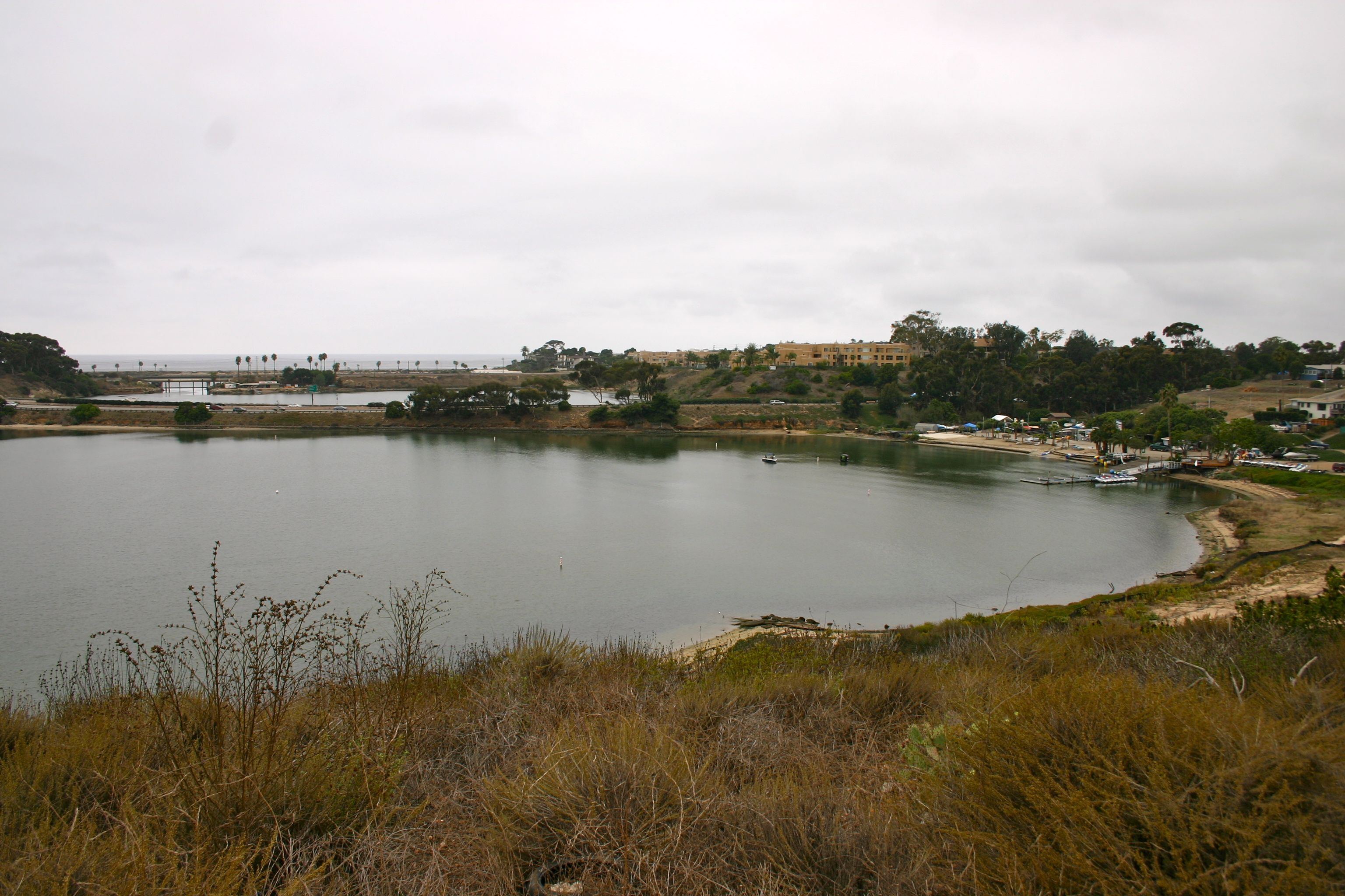 Looking to the west across the middle of Agua Hedionda Lagoon. 
Located on the coast in Carlsbad, San Diego County, Southern California.
From near to far can be seen the I-5, the Coaster line, and Historic Route 101.