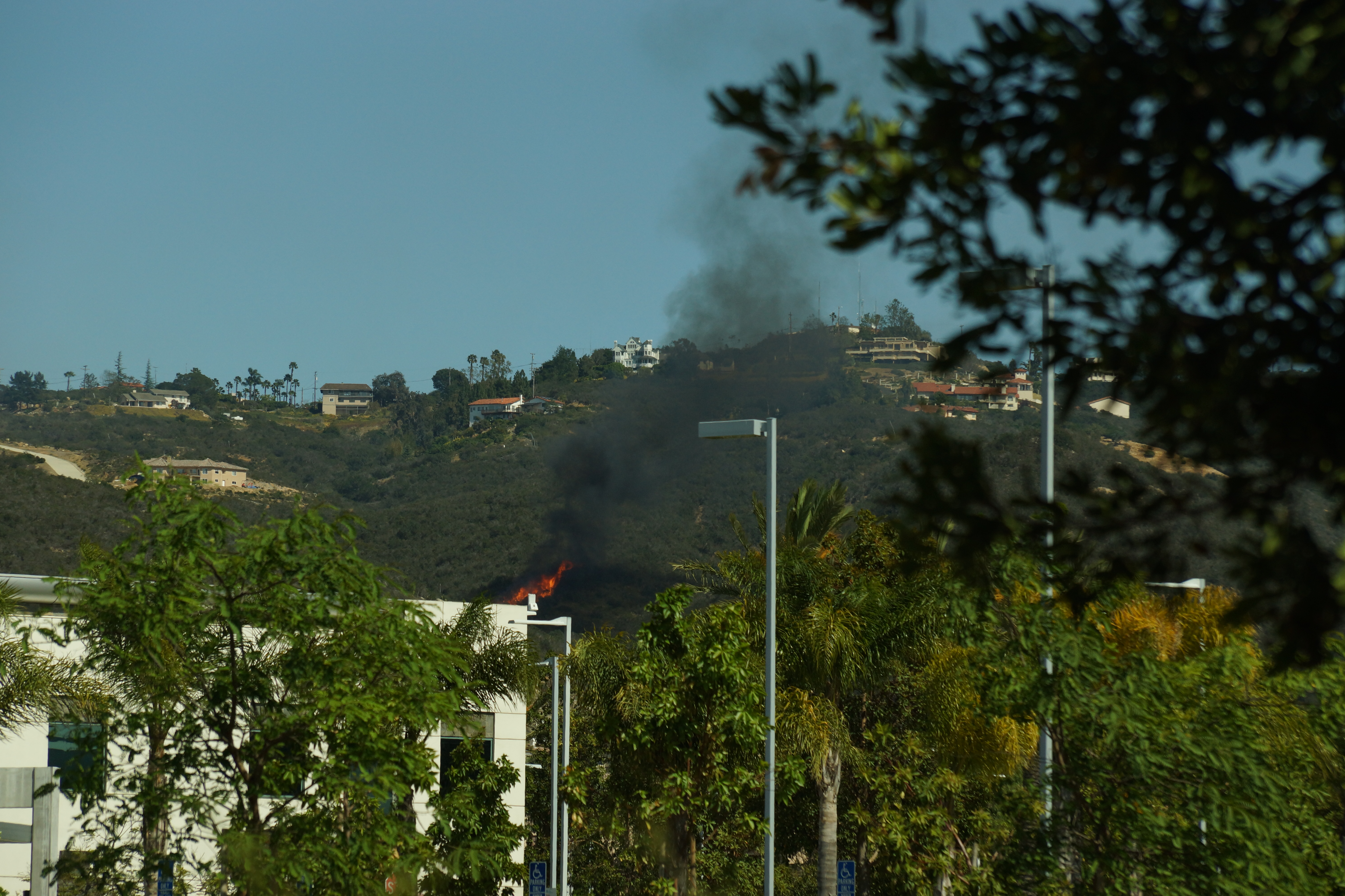 This photo shows the beginning time frame of the Cocos Fire. In the background, up on the hill, is the last remnant smoke from the Washingtonia Fire - whose embers started the Cocos Fire, according to testimony in court. This photo was used in the trial of the juvenile found guilty of setting the fire. Google pin points to San Marcos, California as location.