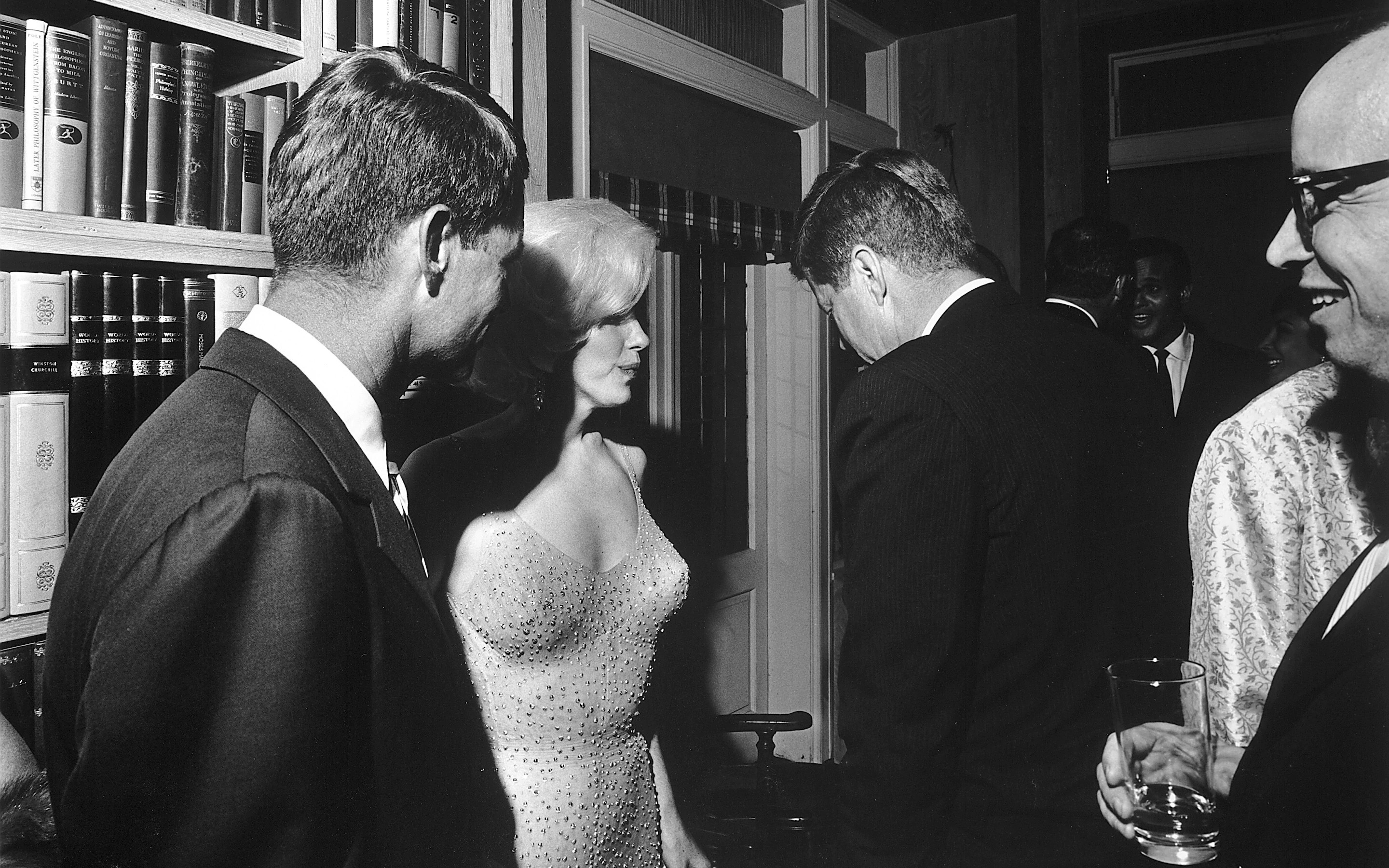 U.S. President John F. Kennedy (with his back to the camera), U.S. Attorney General Robert Kennedy (far left), and actress Marilyn Monroe, on the occasion of President Kennedy's 45th birthday celebrations at Madison Square Garden in New York City.  Arthur M. Schlesinger, Jr. is at the far right.  Facing the camera in the rear appears singer Harry Belafonte.