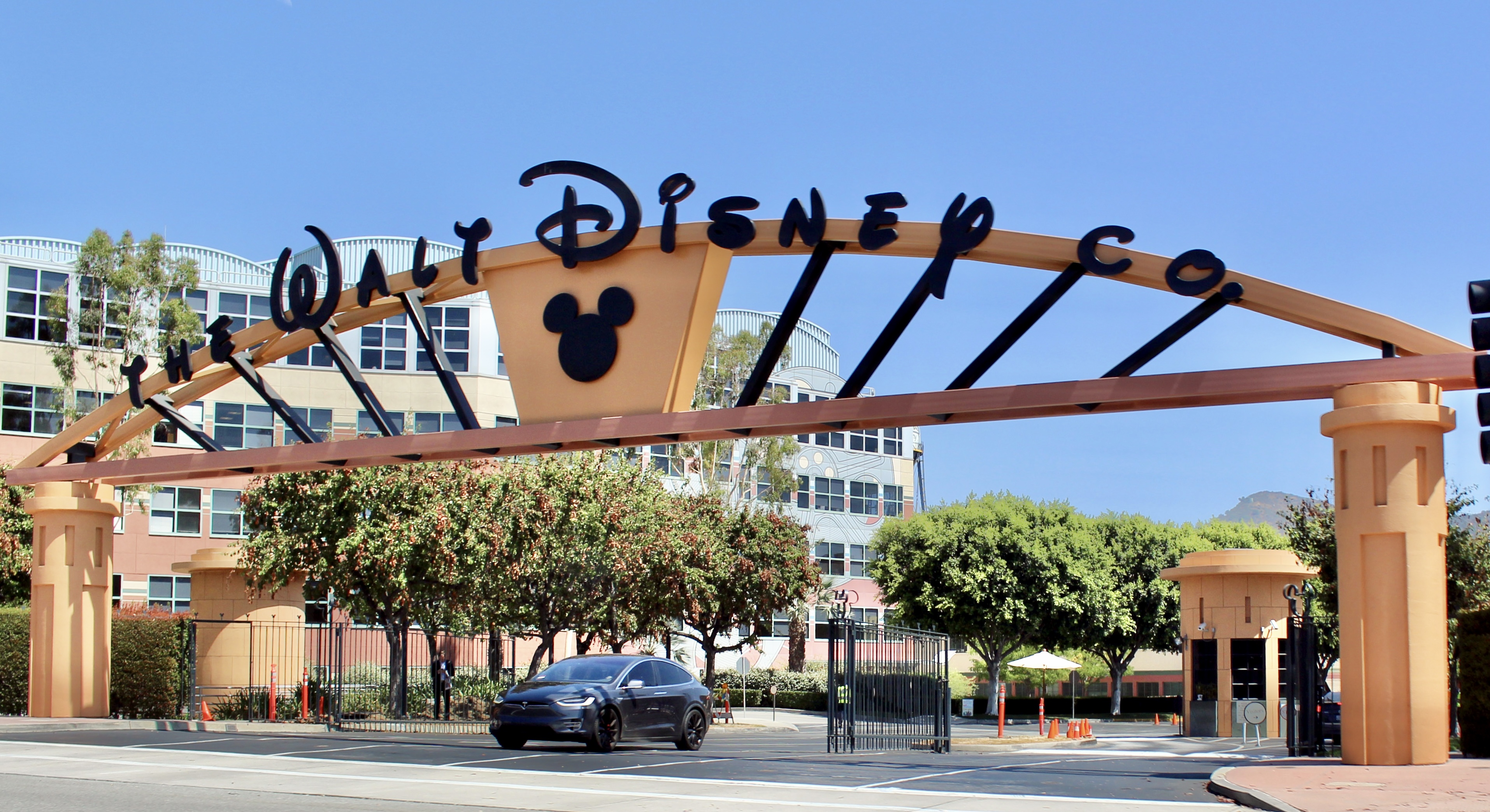 The Alameda Avenue entrance to the Walt Disney Studios in Burbank, California. This was taken just after a major renovation in summer 2016, in which the dated tropical pastels of the gateway arch were replaced with a more conservative orange-and-black color scheme and Mickey Mouse was added to the arch.  Photographed on July 11, 2016 by user Coolcaesar.