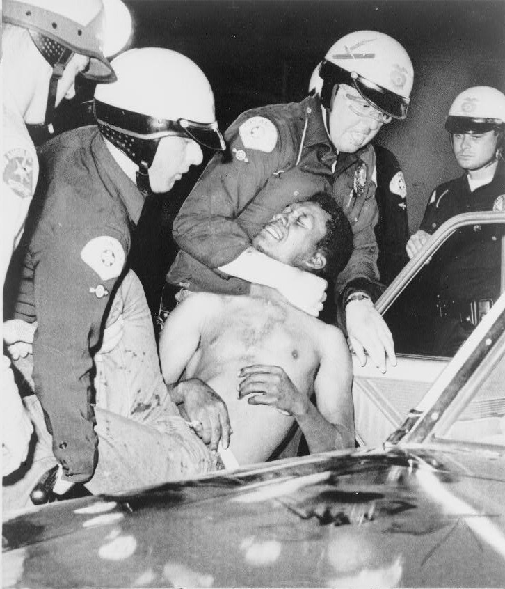 Police arrest a man during the Watts Riots. Image marked as August 12.
