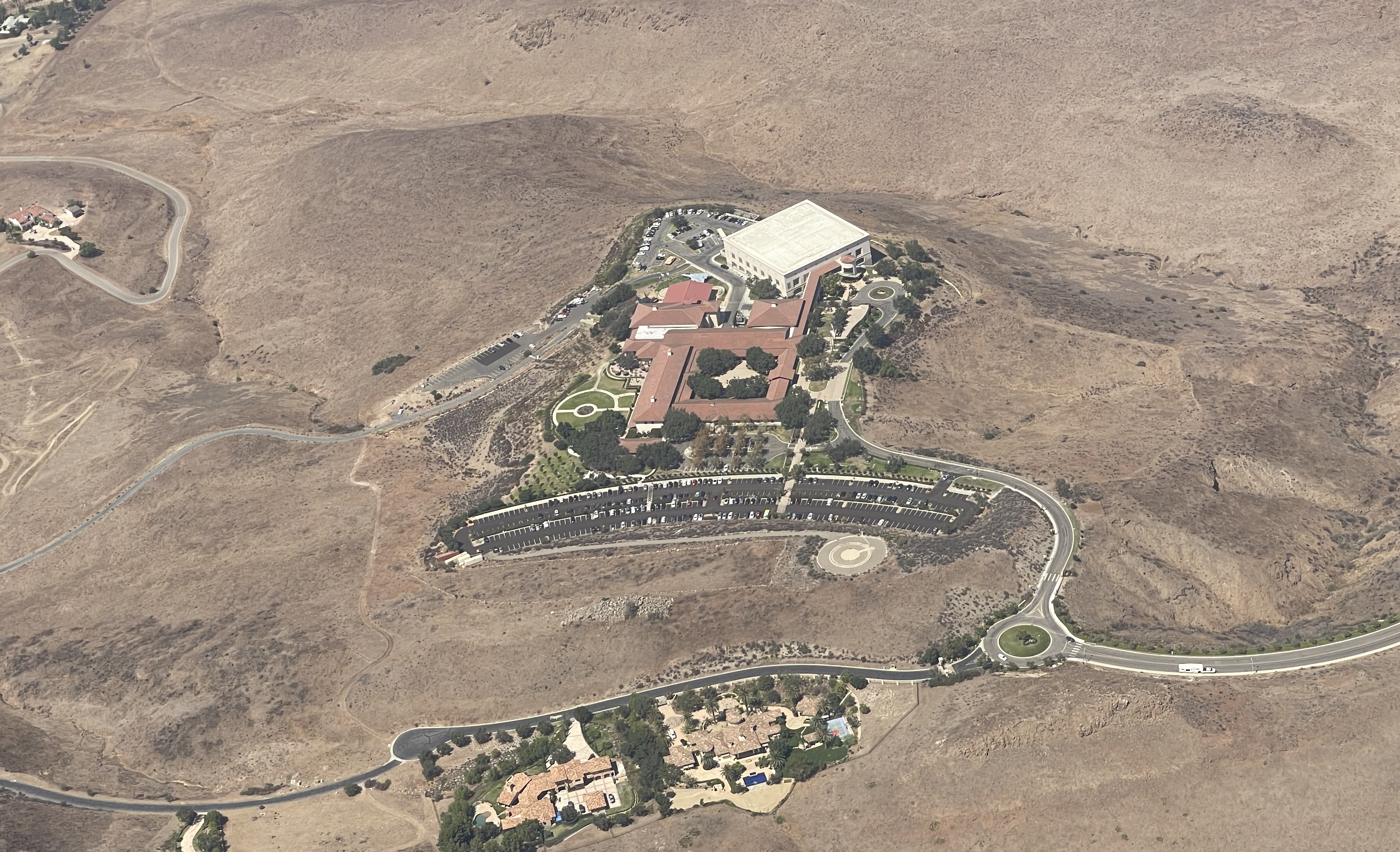 An aerial view of The Ronald Reagan Presidential Library in Simi Valley, CA as observed in 2021 - with Presidential Drive leading up to the site. Library building, Air Force One Pavilion, parking lots, and grounds can be seen. The library's F-14 Tomcat as well as the newly acquired F-117 Nighthawk Stealth Fighter can be seen in this photograph.