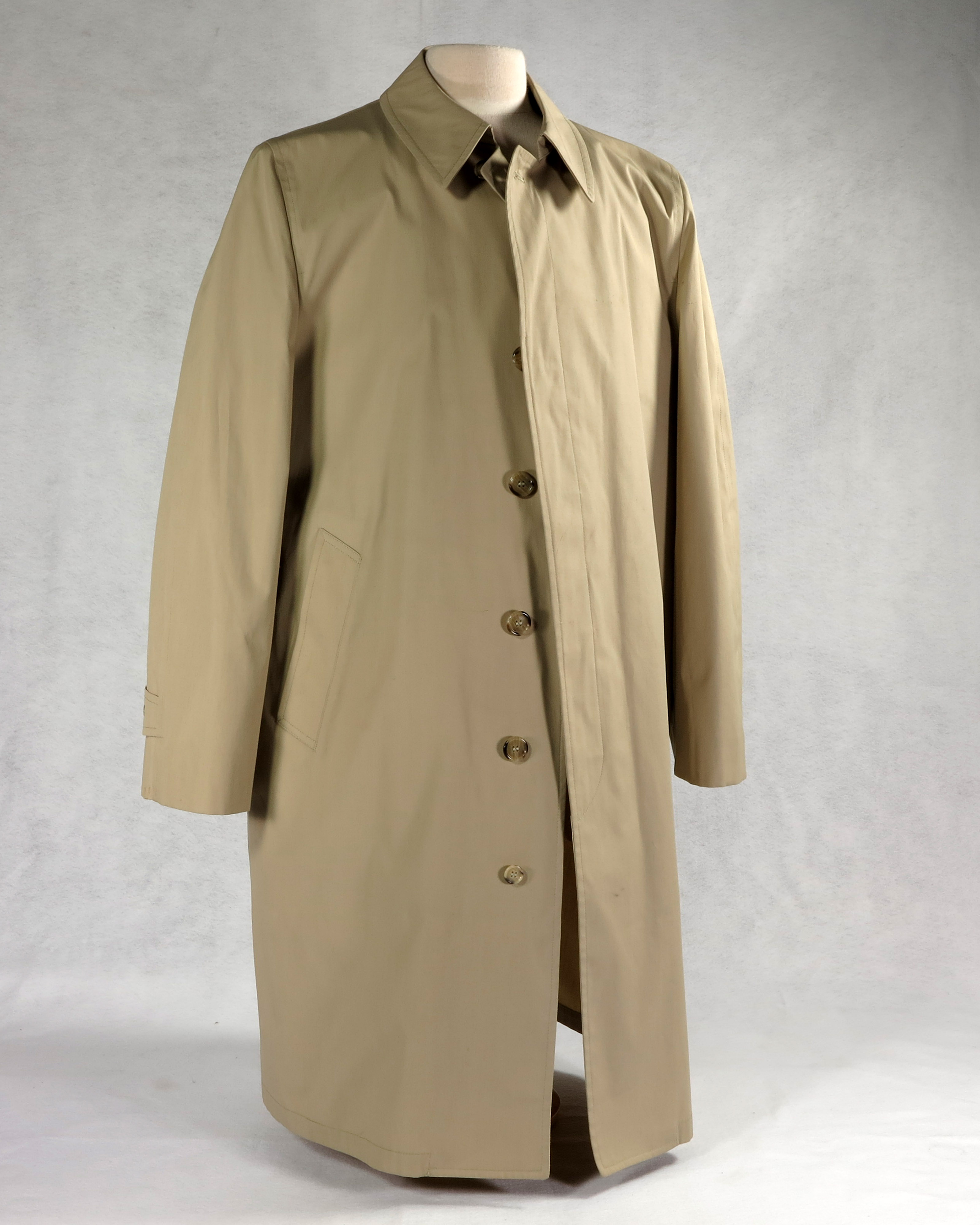 Trench coat containing a bullet-proof vest liner. The coat is beige in color, contains 6 front buttons, adjustable sleeve cuffs, and two pockets, which are accessible from the inside.  The zip-up bullet-proof vest is made of Kevlar and is covered with cloth identical in color to the coat.  Sewn on the front of the vest are cleaning instructions and an issue date of October 1975.  The coat and vest weigh 6 lbs., 15oz.  Worn in public by President Gerald R. Ford after two assassination attempts in 1975.