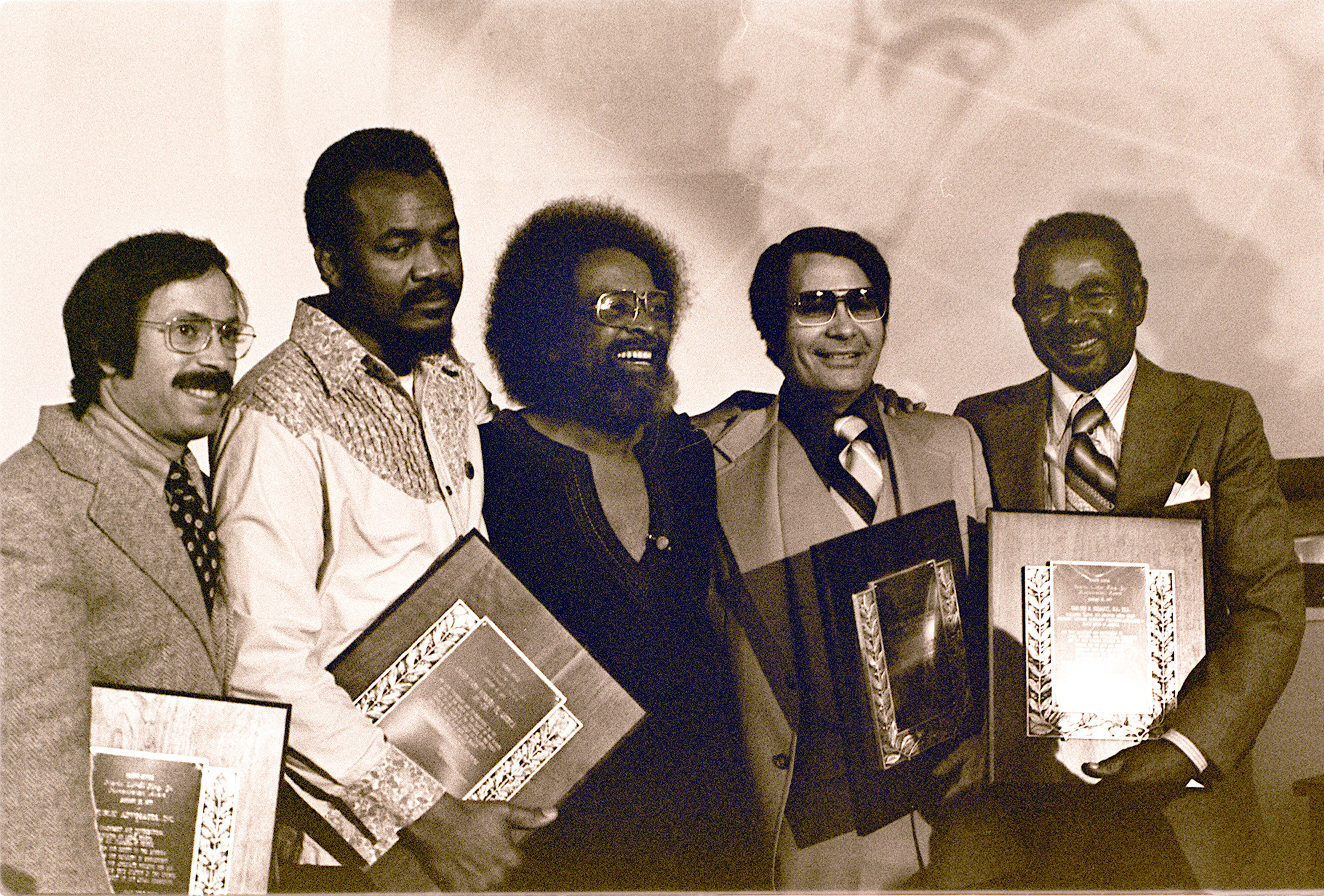 January 1977 photo by Nancy Wong. Reverend Jim Jones of Peoples Temple (2nd from right) is one of the recipients who is given a Martin Luther King, Jr. Humanitarian Award at Glide Memorial Church, 330 Ellis Street by Reverend Cecil Williams (3rd from right) in San Francisco. From left is Bob Gnaizda of Public Advocates, Inc.; Mack Lyons of United Farm Workers Union; and at far right is Dr. Carlton B. Goodlett, publisher of the San Francisco Sun Reporter.