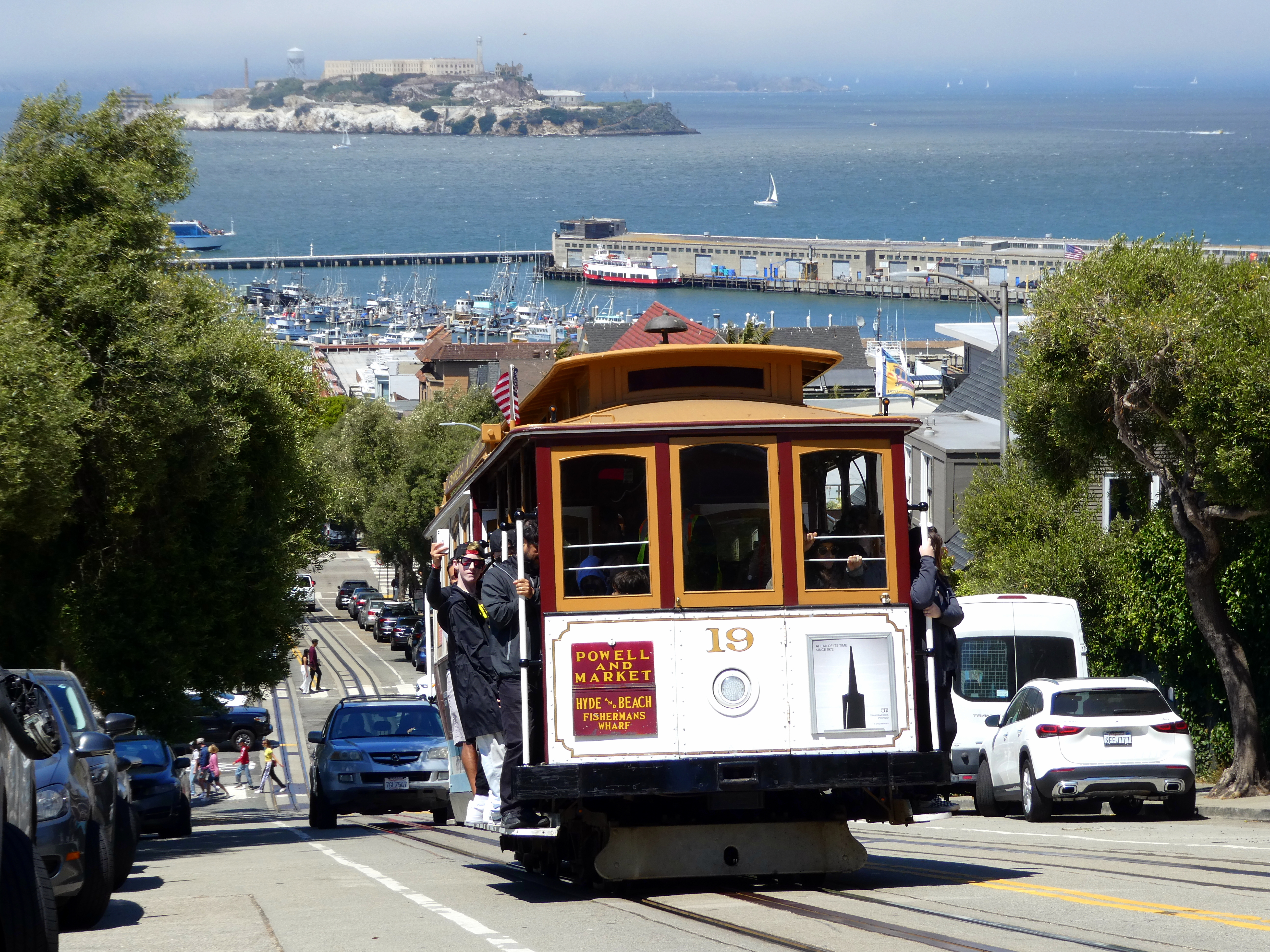 San Francisco cable car #19 operating on Hyde Street in Powell–Hyde service in July 2023. Alcatraz Island and Pier 45 are visible in the background.