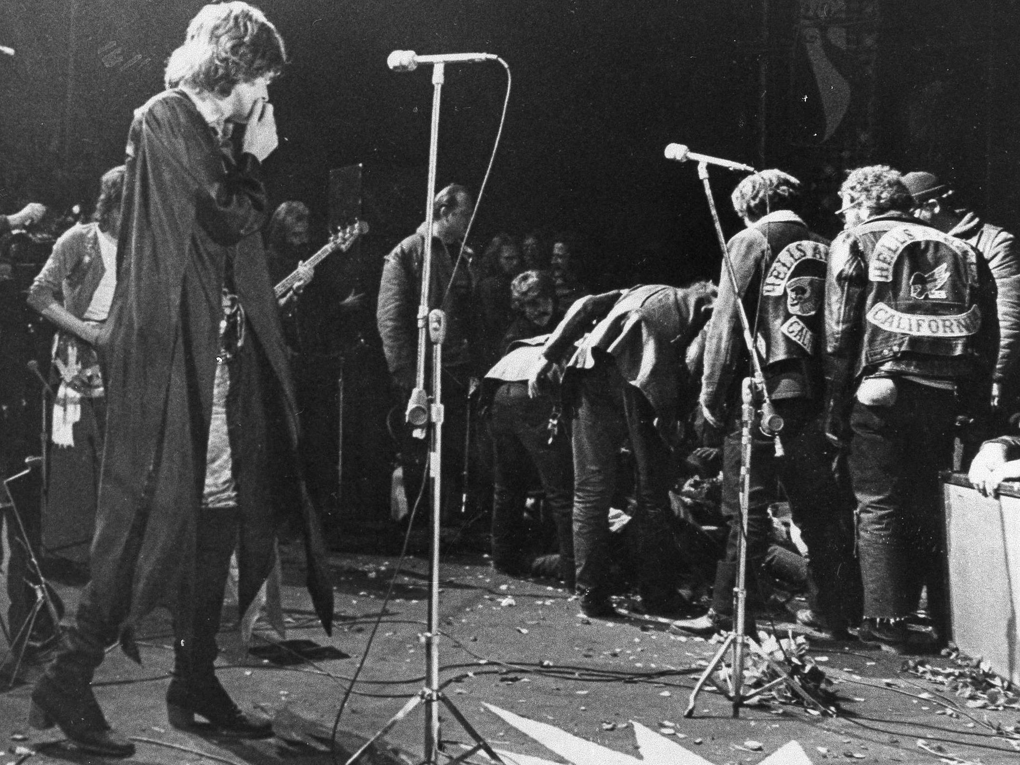 Mick Jagger, on stage at the Altamont Rock Festival on Dec. 6, 1969, watches as Hells Angels cross the stage during a melee to help fellow motorcyclists. The Rolling Stones hired the Hells Angels to police the concert, for $500 worth of beer, but the Angels became violent during the concert. Among other incidents at the concert, the motorcyclists killed one man and dragged another onto the stage and mauled him.