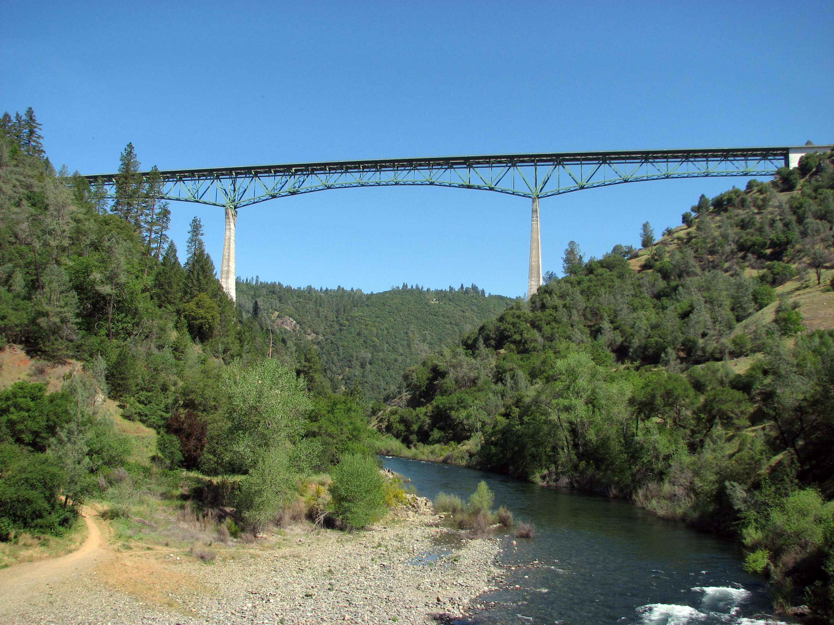 A digital photo of the southern face of the Auburn-Foresthill Bridge (also known as the Foresthill Bridge) taken from the confluence of the North and Middle Forks of the American River located within the Auburn State Recreation Area (near Auburn, California) on April 27, 2008 at 10:23:58 AM Pacific Daylight Time.