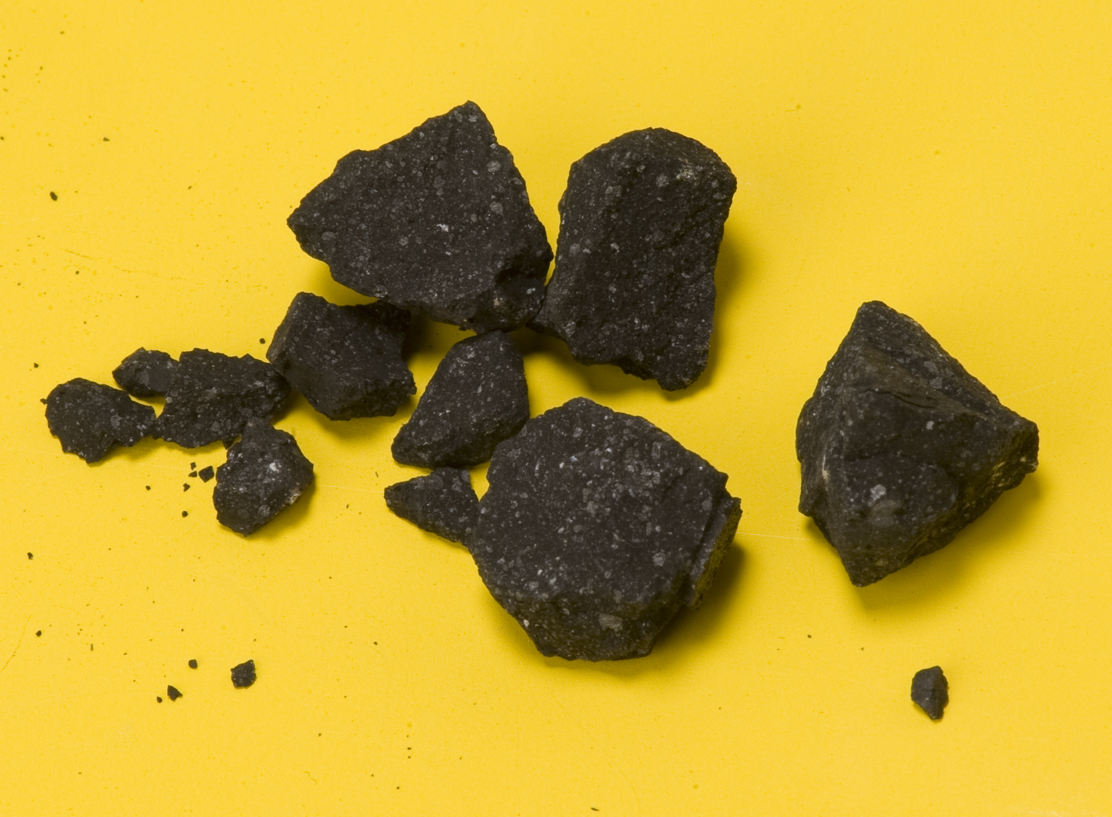Fragments of of a crushed 4 gram meteorite (SM2) belonging to the Sutter's Mill meteorite, which is thought to be a rare CM type carbonaceous chondrite. The fragments were obtained from the parking lot of Henningsen Lotus Park in Lotus, California, near Sutter's Mill, by astronomer Peter Jenniskens. The white specks are calcium aluminium inclusions.