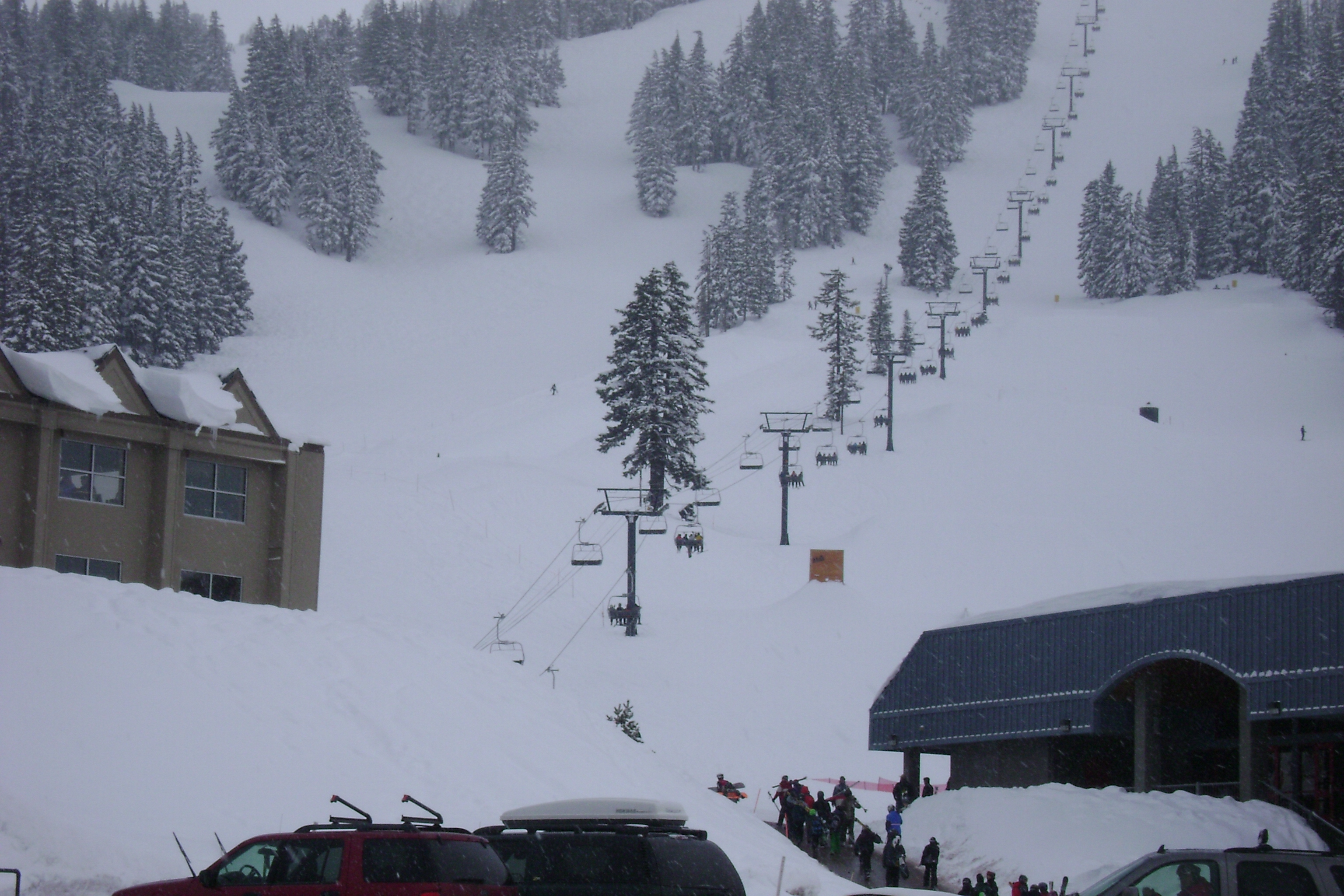 Pine Marten Express, a high-speed quad chairlift made by Doppelmayr CTEC at Mt. Bachelor Ski Area. On the left is the West Village Lodge, also called the main lodge. On the right is Bachelor Ski &amp; Sport Shop, the largest retailer of it's kind in the pacific northwest. This photo was tooken from the parking lot.
