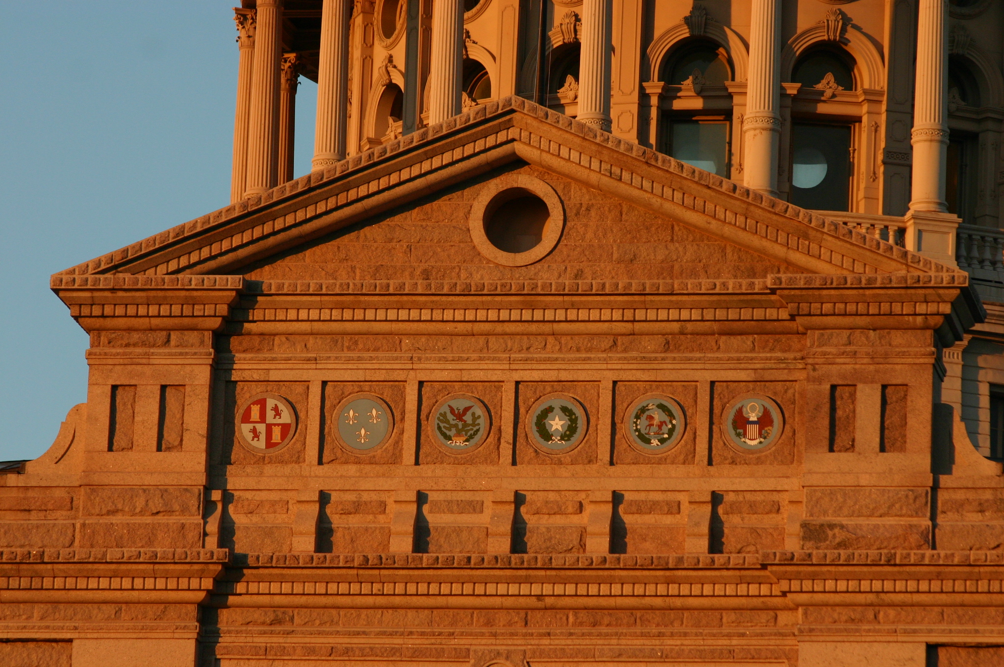 Six flags over Texas emblems displayed under the Texas State Capitol Dome, representing the six regimes that have ruled the land which is now Texas since the early 16th century. From left to right, they are the Kingdom of Spain, the Kingdom of France, the Republic of Mexico, the Republic of Texas, the Confederate States of America, and the United States of America respectively. Taken during sunset for the saturated color effect.