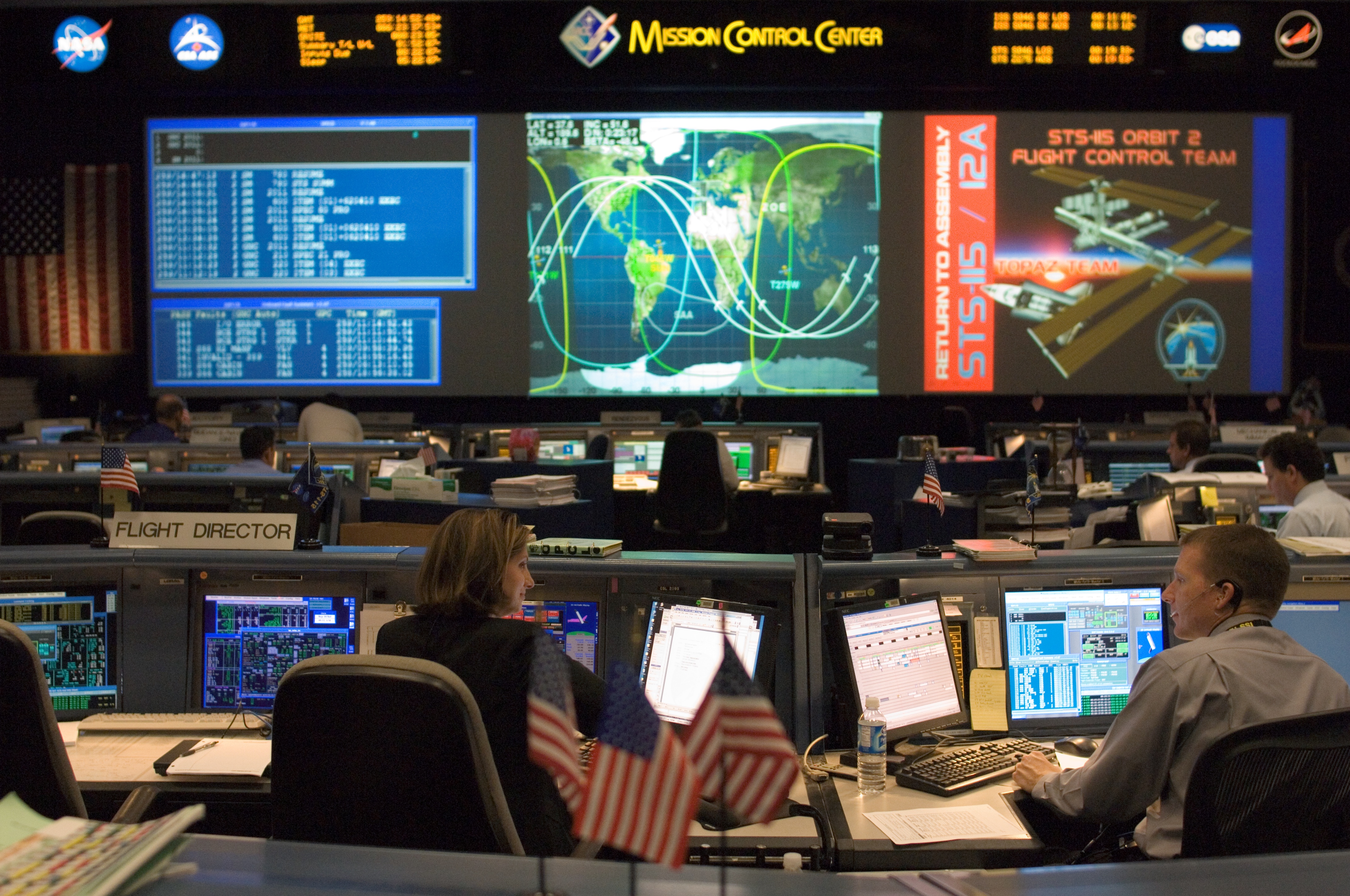 Flight director Catherine A. Koerner (left foreground) and astronaut Terry W. Virts, Jr., spacecraft communicator (CAPCOM), monitor data at their consoles in the Shuttle (White) Flight Control Room of Houston's Mission Control Center during STS-115 flight day eight activities.