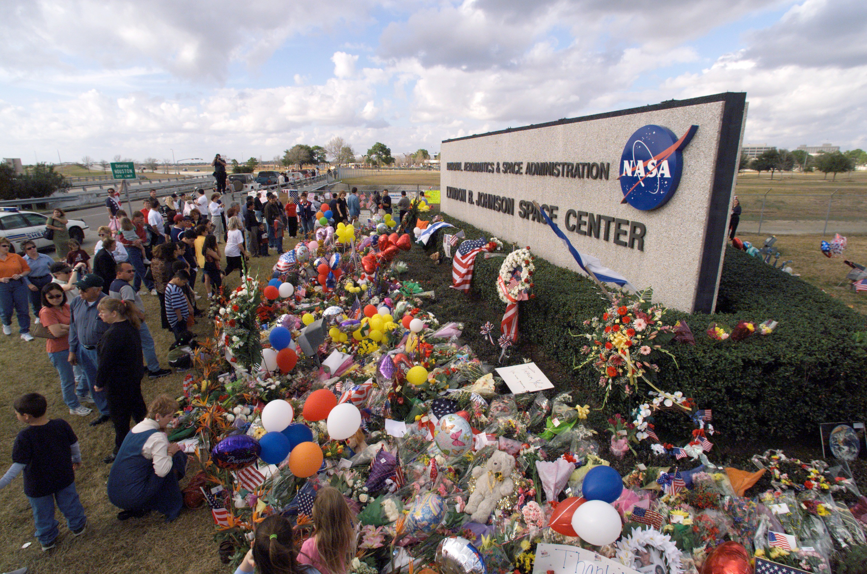 In memory of the Space Shuttle Columbia crewmembers who lost their lives on February 1, 2003, a massive collection of flowers, balloons, flags, signs, and other arrangements were placed at the Johnson Space Center sign at the Center's main entrance.