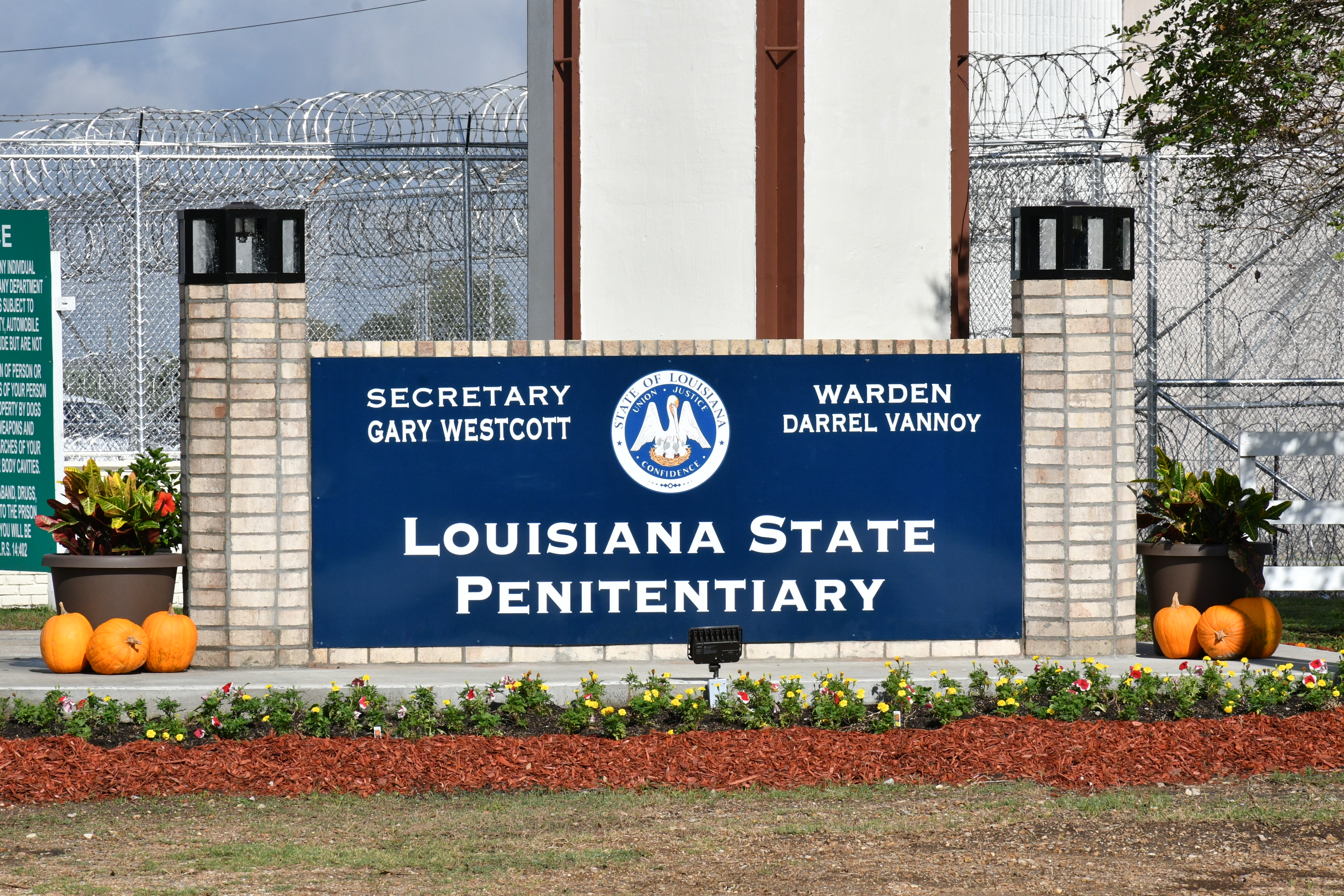 The entrance sign to Louisiana State Penitentiary states "Louisiana State Penitentiary" Secretary Gary Westcott and Warden Darrel Vannoy along with the State of Louisiana seal.