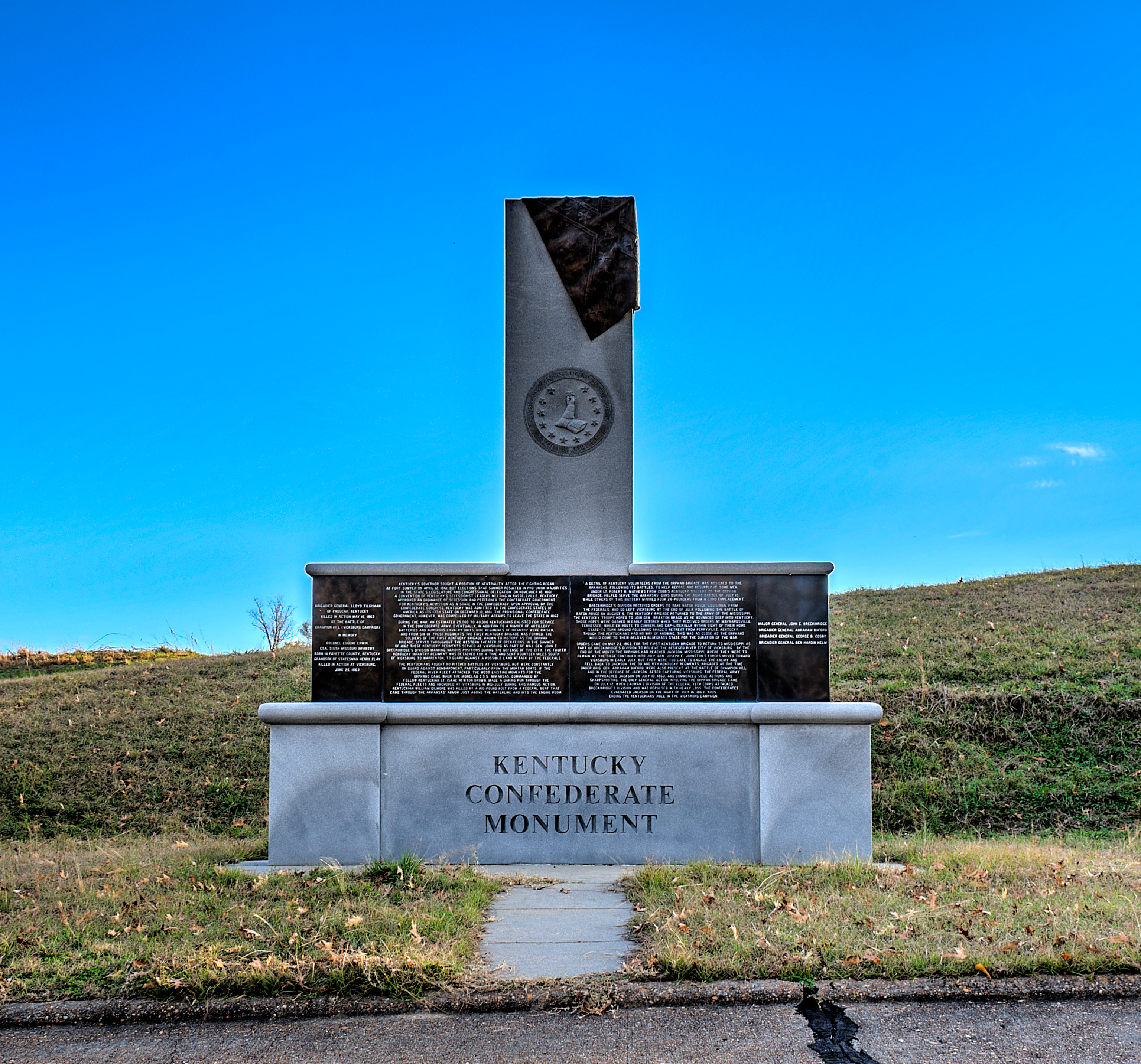 Left Panel
Brigadier General Lloyd Tilghman of Paducah, Kentucky
Killed in Action May 16, 1863 at the Battle of Cahmpion Hill (Vicksburg Campaign)
In Memory
Colonel Eugene Erwin, CSA, Sixth Missouri Infantry
Born in Fayette County, Kentucky
Grandson of Statesman Henry Clay
Killed in action at Vicksburg, June 25, 1863
Center Panels
Kentucky's governor sought a position of Neutrality after the fighting began at Fort Sumter on April 12, 1861, but elections that summer resulted in pro-Union majorities in the state legislature and congressional delegation. On November 18, 1861, a convention of Kentucky's secessionist leaders meeting in Russellville, Kentucky, approved an ordinance of secession and petitioned the Confederate government for Kentucky's admission as a state in the Confederacy. Upon approval by the Confederate congress, Kentucky was admitted to the Confederate States of America as its 13th state on December 10, 1861. The provisional Confederate government, however, was compelled by military affairs to leave the state in 1861.
During the war, an estimated 25,000 to 40,000 Kentuckians enlisted for service in the Confederate Army. Eventually, in addition to a number of artillery batteries and numerous cavalry units, nine regiments of infantry were raised, and from six of these regiments the first Kentucky brigade was formed. The soldiers of the first Kentucky brigade, known to history as the Orphan Brigade, served throughout the Western theater of operations. In the summer of 1862 these Kentucky regiments served at Vicksburg as part of Maj. Gen. John C. Breckinridge's division manning various positions during the defense of the city. The fourth Kentucky infantry regiment was detached for a time and sent fourteen miles south of Vicksburg to Warrenton, to guard against a possible land attack by the Federals.
The Kentuckians fought no pitched battles at Vicksburg, but were constantly on guard against bombardment particularly from the mortar boats, if the Federal river fleet attacked. The most exciting moments for the orphans came when the ironclad C.S.S. Arkansas, commanded by fellow Kentuckian Lt. Isaac Newton Brown, made a daring run through the Federal fleets and anchored at Vicksburg in mid-July. During this famous action, Kentuckian William Gilmore was killed by a 160-pound bold from a Federal boat that came through the Arkansas' armor just above the waterline and into the engine room.
A detail of Kentucky volunteers from the Orphan Brigade was assigned to the Arkansas, following its battles, to help recoal and resupply it. Some men under Lt. Rubert B. Mathews from Cobb’s Kentucky Battery of the Orphan Brigade, helped serve the Arkansas’ guns during the night battle of July 15, while others of this battery manned four 24-pounders from a land emplacement.
Breckinridge’s division received order to take Baton Rouge, Louisiana, from the Federals, and so left Vicksburg at the end of July. Following the Battle of Baton Rouge, the Kentucky brigade returned to the Army of the Mississippi. The Kentucky troops hoped to join Braxton Bragg as he advanced deep into Kentucky. Those hopes were dashed when they received orders at Maynardsville, Tennessee, when en route to Cumberland Gap literally within sight of their home state to turn around following Bragg’s retreat from Perryville, Kentucky. Though the Kentuckians had no way of knowing, this was as close as the Orphans would come to their beloved Bluegrass State for the duration of the war.
Orders came on May 23, 1863, for the first Kentucky Brigade to return to Vicksburg as part of Breckinridge’s Division to relieve the besieged river city. By the end of the month the Orphans had reached Jackson, Mississippi, where they were to remain as the siege continued into July. Gen. Joseph E. Johnston’s forces moved toward Vicksburg in early July, but they were too late to engage the enemy, and they fell back to Jackson. The 3rd and 8th Kentucky Regiments, brigaded at the time under Gen. Abraham Buford, were also present at the Battle of Champion Hill and in the defense of Jackson. After capturing Vicksburg, the Federal Army approached Jackson on July 10, 1863, and commenced siege actions and sharpshooting. The only general action involving the Orphan Brigade came on July 12, when Lauman’s Division of the Federal 13th Corps attacked Breckinridge’s Division and was repulsed with heavy loss. The Confederates evacuated Jackson on the night of July 13, 1863, thus ending the Kentuckians’ role in the Vicksburg campaign.
Right Panel
Major General John C. Breckinridge
Brigadier General Abraham Buford
Brigadier General George B. Cosby
Brigadier General Ben Hardin Helm