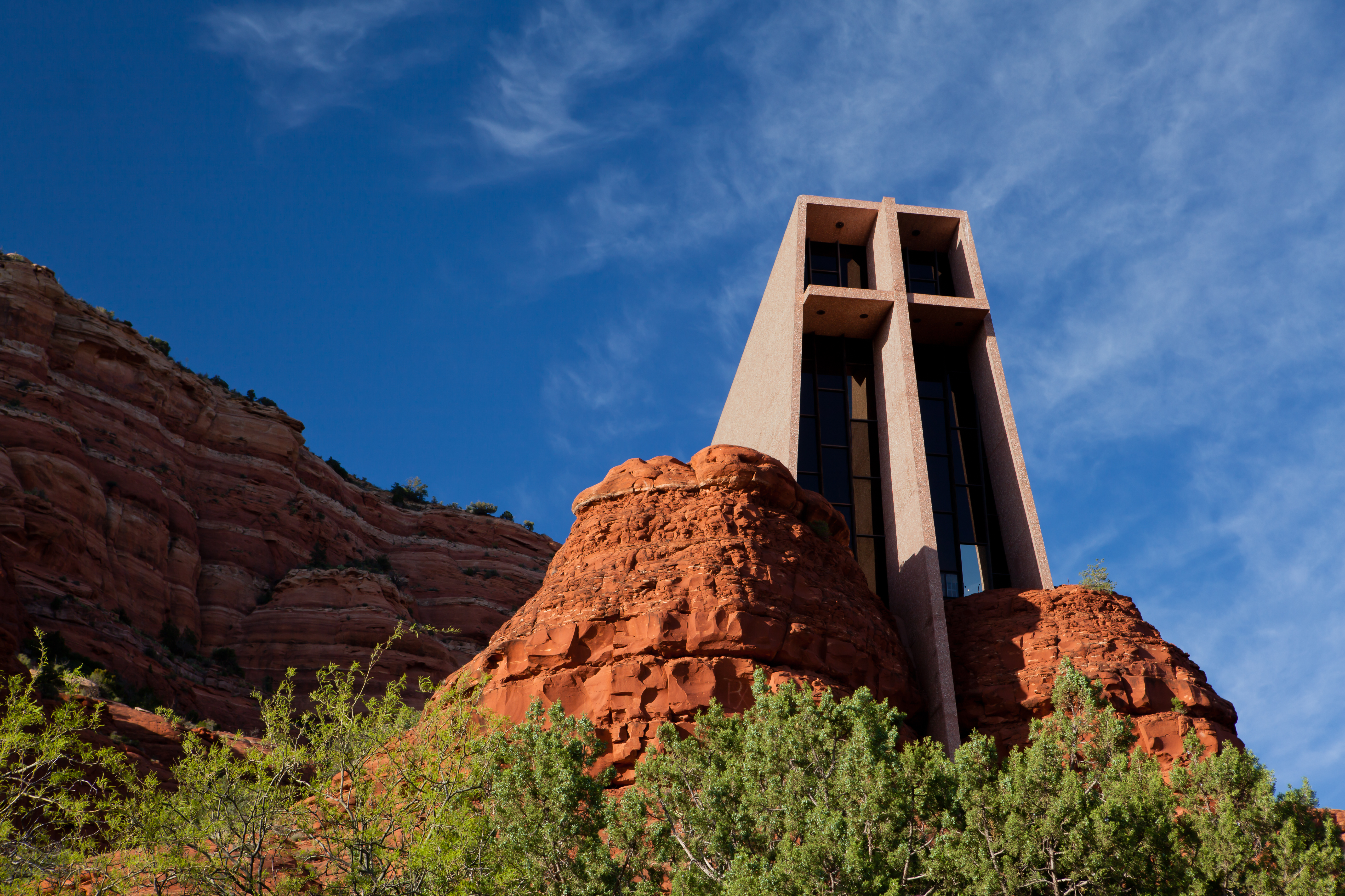 A picture of the Chapel of the Holy Cross in Sedona, Arizona near sunset. The chapel appears to rise out of the rock formations characteristic of the area.