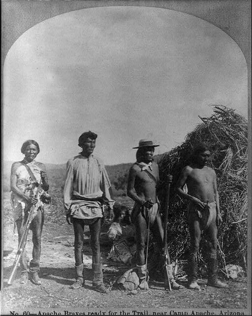 "Apache braves ready for the trail, near Camp Apache, Arizona." An 1873 stereograph, a wickiup is in the background.