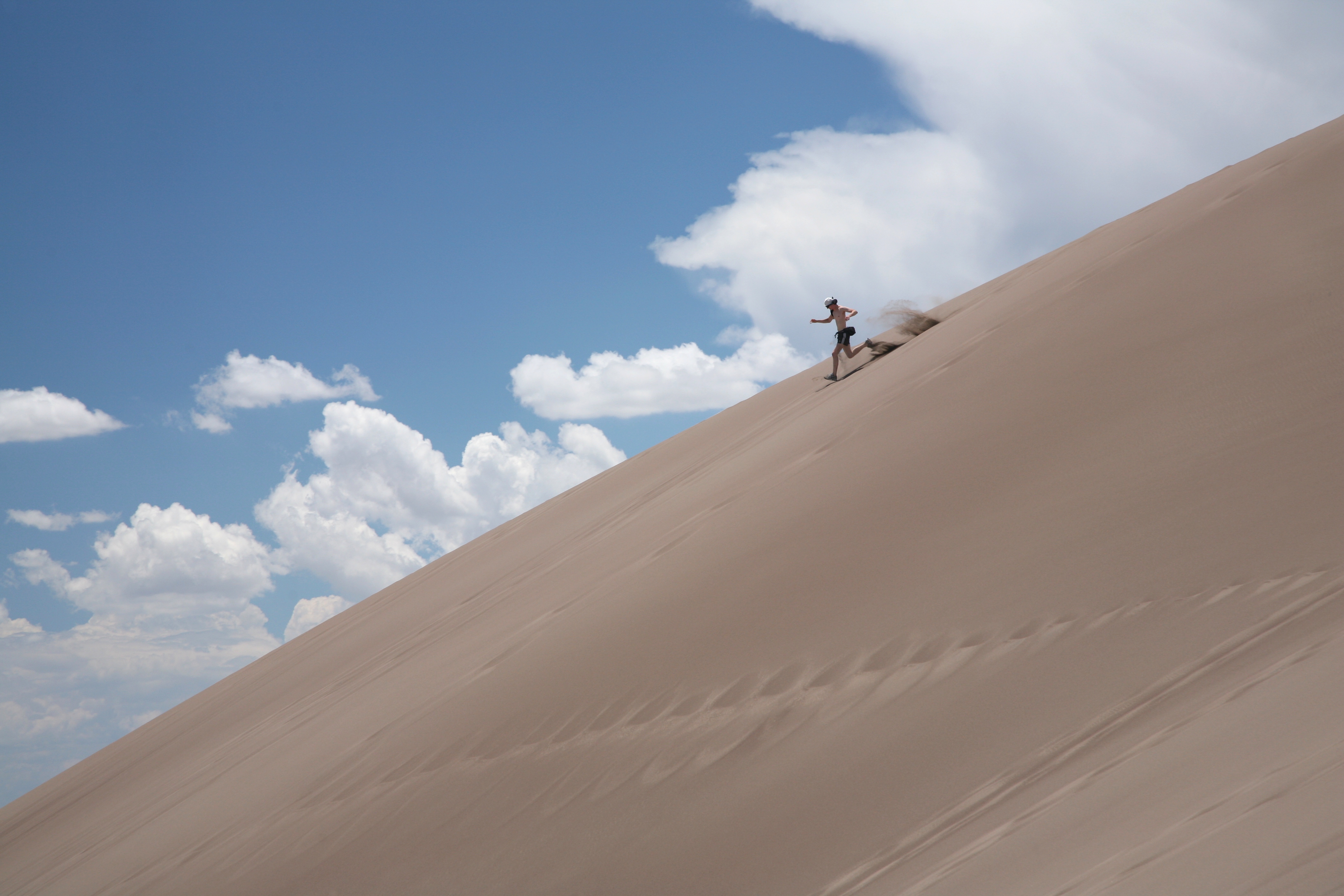 Visitor running down a dune in Great Sand Dunes National Park.