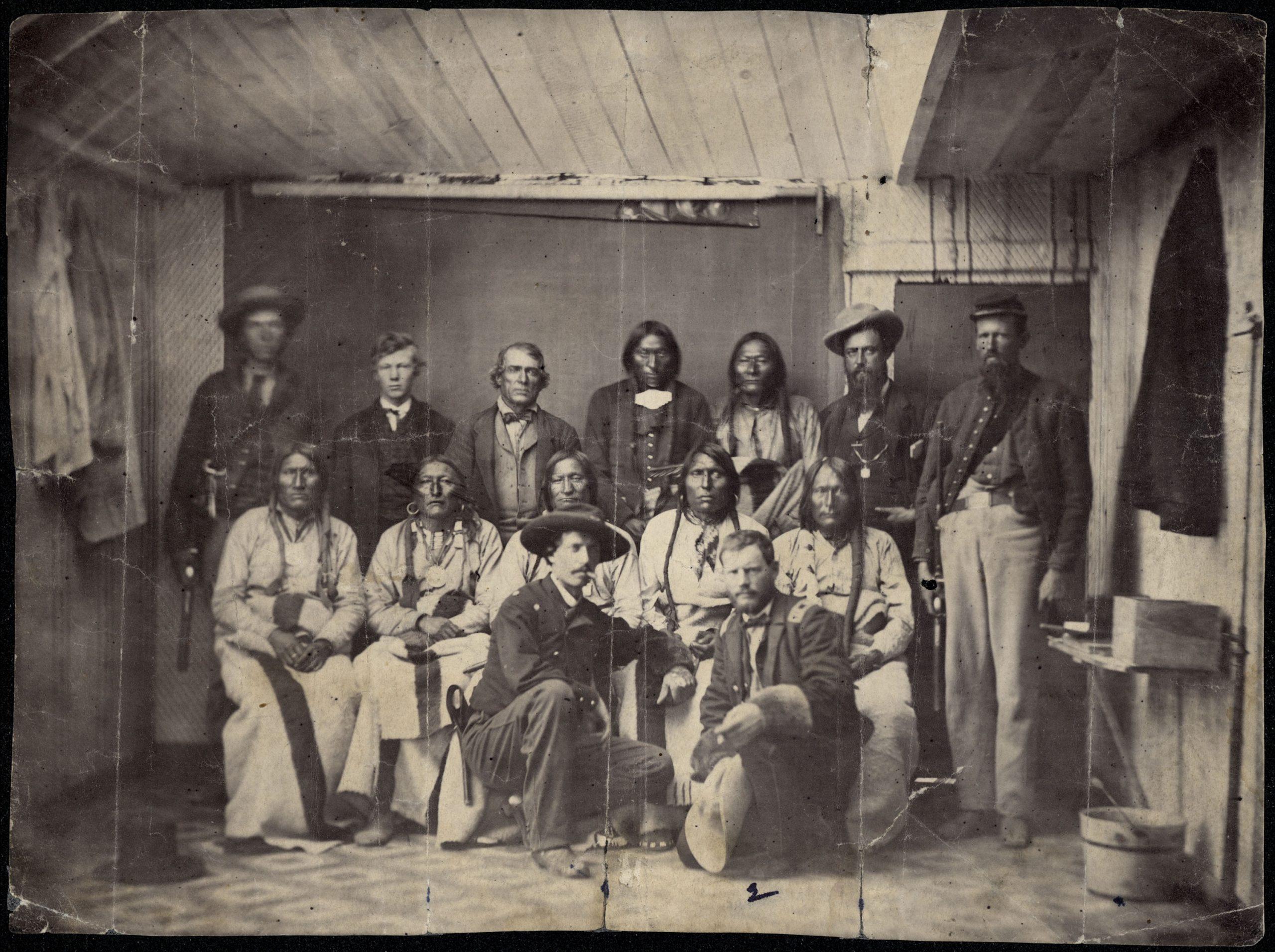 Camp Weld Conference
This rare photograph by an unknown photographer shows the ill-fated Cheyenne chief, Black Kettle, and a number of his associated at Camp Weld, on the outskirts of Denver. They had assembled there on September 28, 1864, for a peace council with Governor Evans and Colonel John M. Chivington, commander of the District of Colorardo. Chivington later attacked their camp in what is known as the Sand Creek massacre. 
Some of the identifications of Indians are uncertain. Front row, kneeling, left to right: Major Edward W. Wynkoop, commander at Fort Lyon and later agent for the Cheyennes and Arapahoes; Captain Silas S. Soule, provost marshal, later murdered in Denver. Middle row, seated, left to right: White Antelope (or perhaps White Wolf), Bull Bear, Black Kettle, One Eye, Natame (Arapaho). Back row, standing, left to right: Colorado militiaman, unknown civilian, John H. Smith (interpreter), Heap of Buffalo (Arapaho), Neva (Arapaho), unknown civilian, sentry. Another identification states that Neva is seated on the left and the Indian next to Smith is White Wolf (Cheyenne).— Library, State Historical Society of Colorado, In: Wilbur Sturtevant Nye, Plains Indian raiders : the final phases of warfare from the Arkansas to the Red River, with original photographs by William S. Soule. University of Oklahoma Press, 1st edition, 1968, ISBN 0806111755, p188.