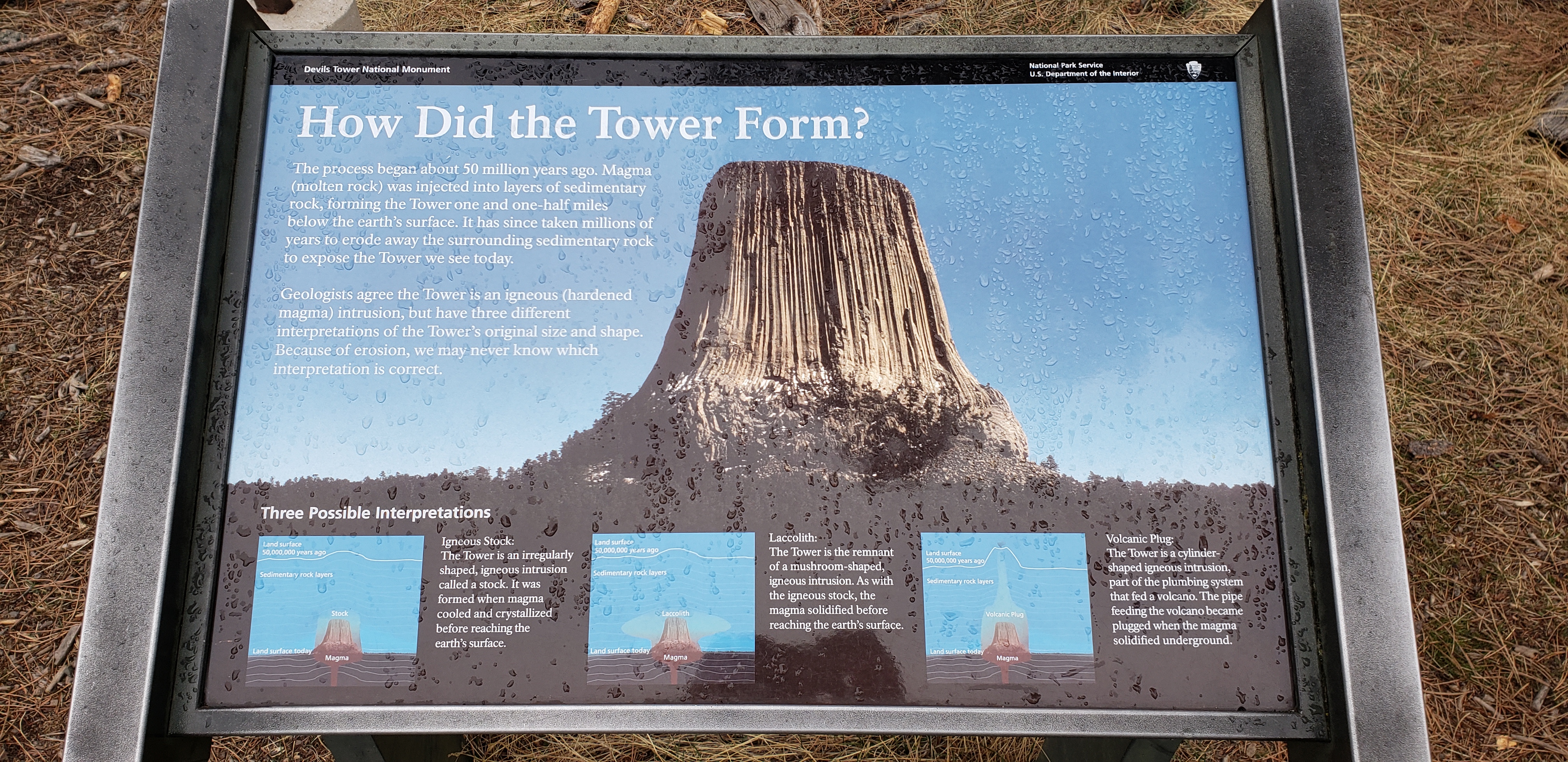 Devils Tower National Park sign describing the three possible origins: stock, laccolith or volcanic plug