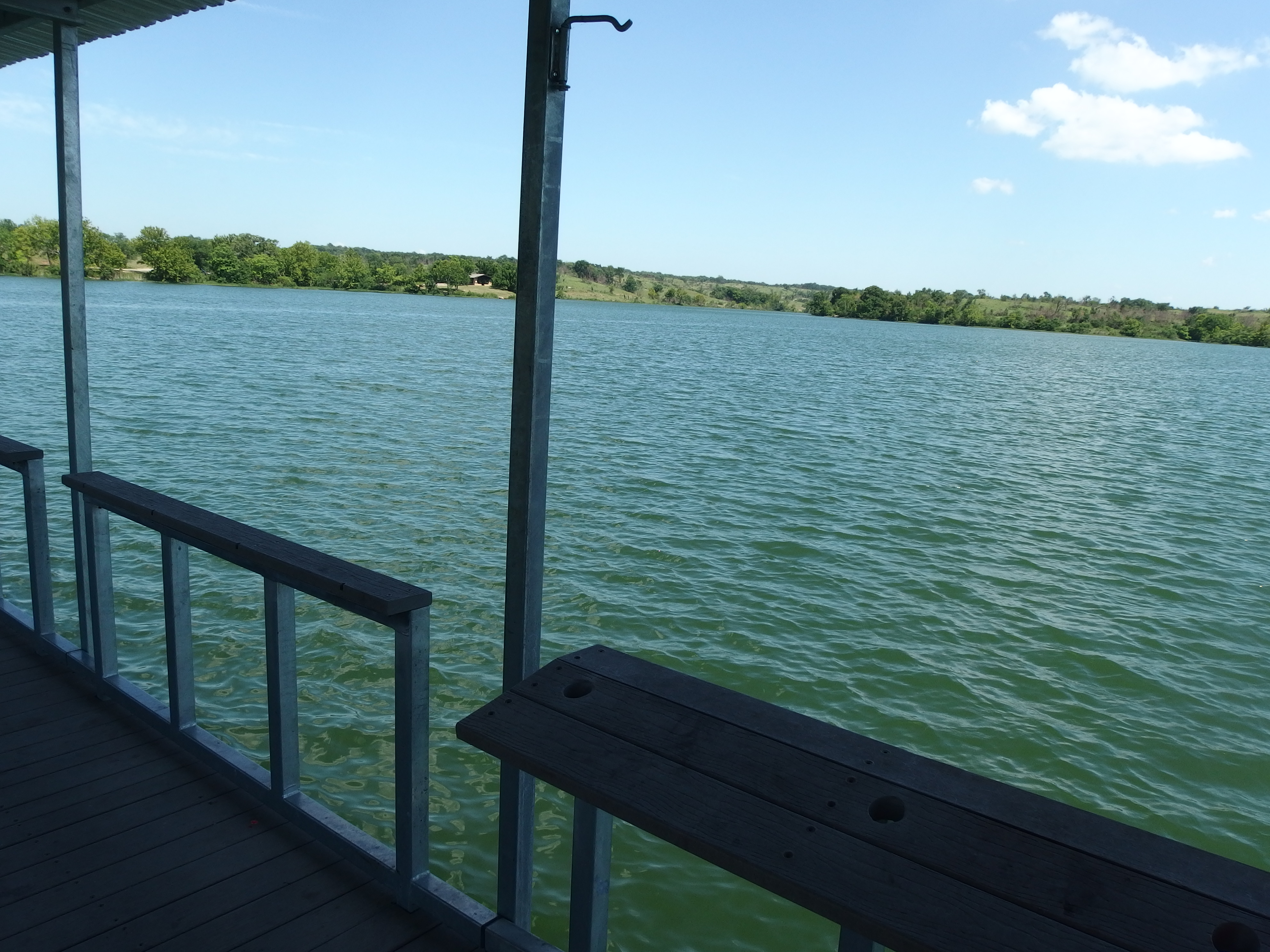 A view from and of the fishing dock on Veterans Lake in Chickasaw National Recreation Area, showing the water and the shoreline to the east.