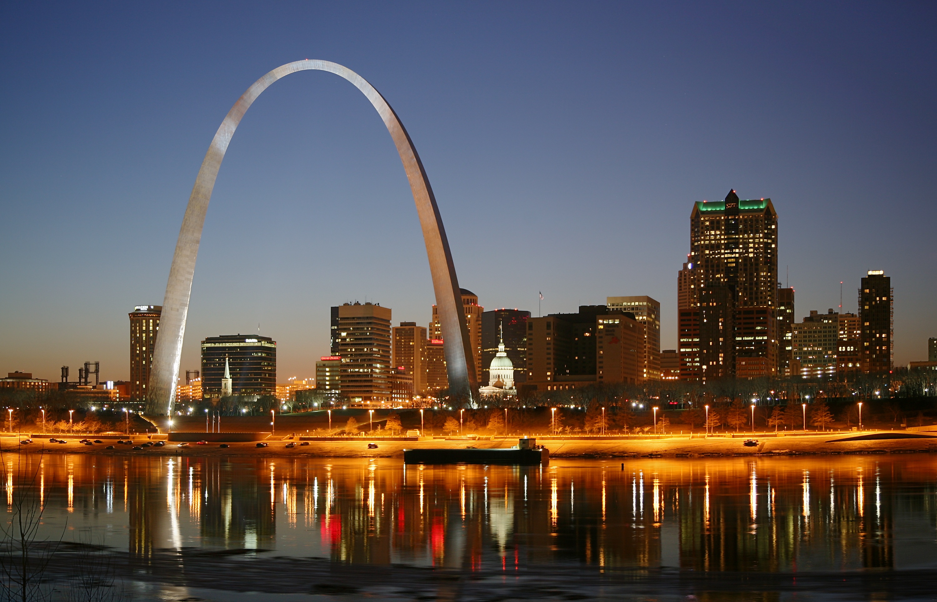 St. Louis on the Mississippi river by night. Jefferson National Expansion Memorial aka. Gateway Arch and Old Courthouse are visible.