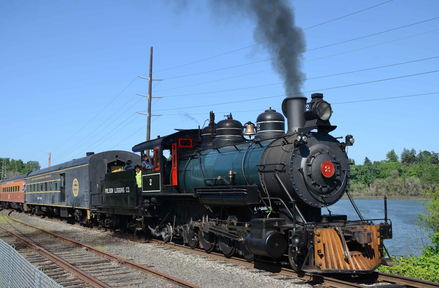 Polson Logging Company No. 2, a 1912 steam locomotive on temporary loan to the Oregon Rail Heritage Foundation (and based at the Oregon Rail Heritage Center in Portland, Oregon), heading an excursion train southbound on the Oregon Pacific Railroad track near Oaks Amusement Park (behind the photographer) and Oaks Bottom Wildlife Refuge (in the background of this photo) in May 2023.
