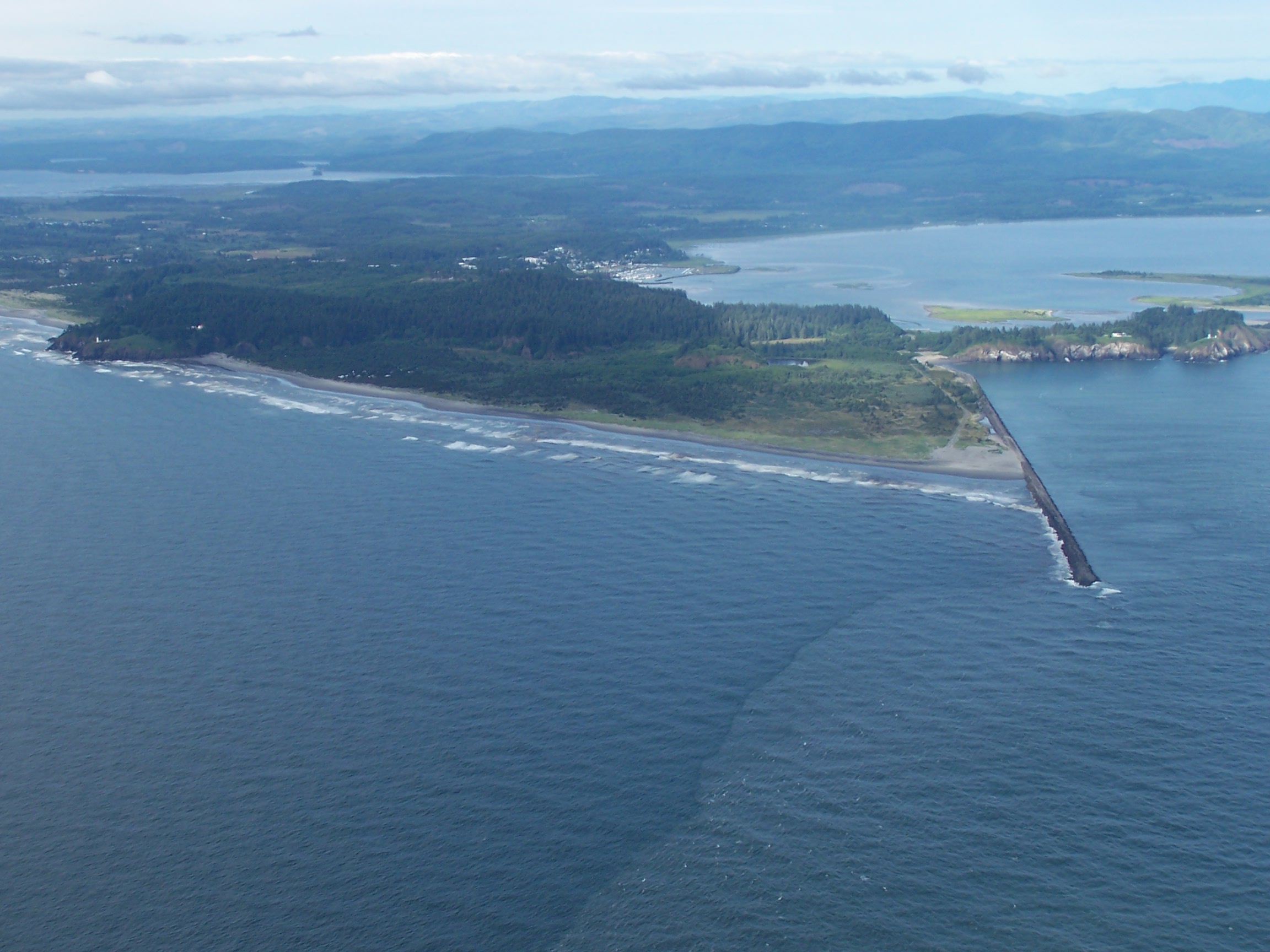Cape Disappointment, Washington, at the mouth of the Columbia River on the Pacific Ocean. View is to the northeast. The town of Ilwaco, Washington is at upper center. The Pacific Ocean is in front and the mouth of the Columbia is at right. The southern portion of Willapa Bay can be seen at upper left.