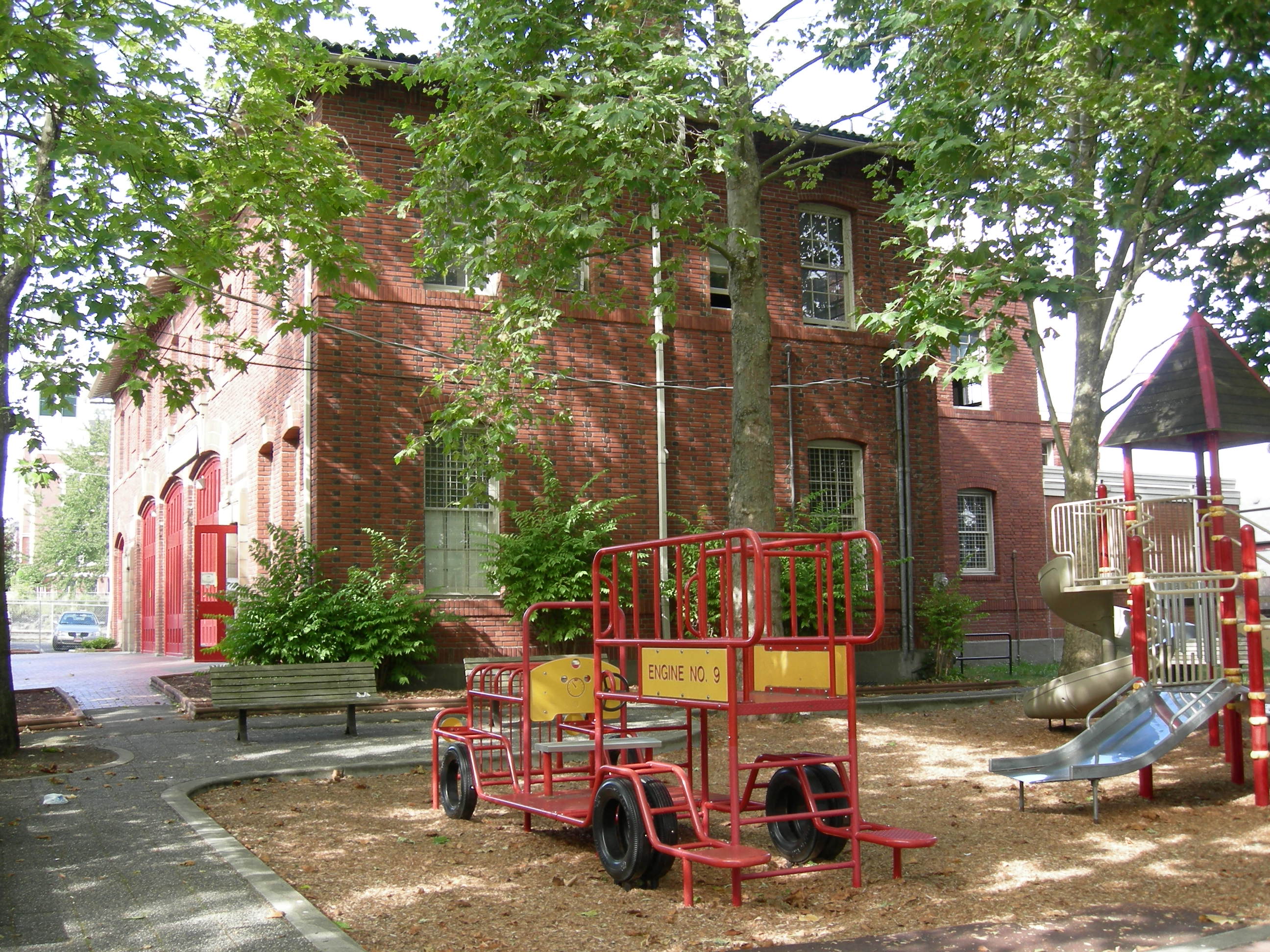 Playground in Firehouse Mini Park and, in background, the "CAMP Firehouse": the former Firehouse No. 23, Seattle, Washington, headquarters of Seattle's Byrd Barr Place (formerly Central Area Motivation Program), which is on the National Register of Historic Places.