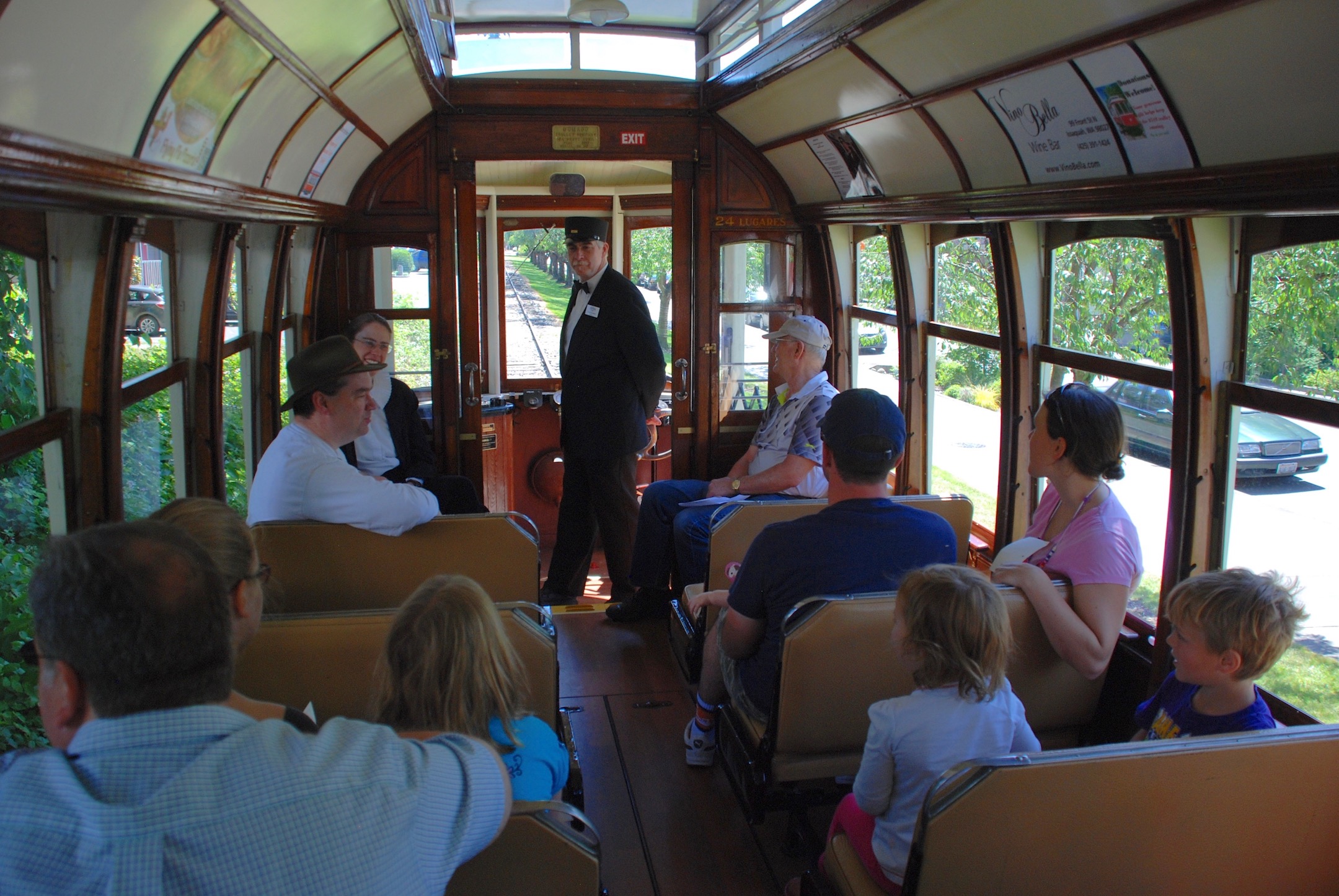 Interior of Issaquah Valley Trolley car 519 loaded with passengers during a trip on the line. Car 519 is ex-Lisbon No. 519 and was built in kit form by the American J. G. Brill Company and assembled in Portugal in 1925.  One remnant of its service career in Portugal still visible here is the lettering "24 lugares" (located just to the right of the motorman), which is Portuguese for "24 seats", the car's seating capacity.