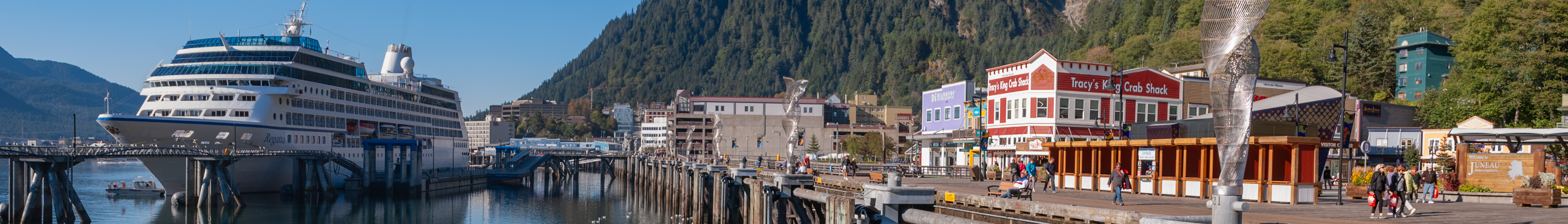 Oceania cruise ship, REGATTA - IMO 9156474, at the dock that runs the length of the harbor in Juneau, Alaska USA. 
Note: There are ten 20-foot-high, stainless steel sculptures mounted on the mooring dolphins the cruise ships tie up to. They are called ‘Aquileans’ by the sculptor, Cliff Garten. 
Note: This image was extracted as a 7:1 banner intended for Wikivoyage topic of "Juneau", Alaska USA.