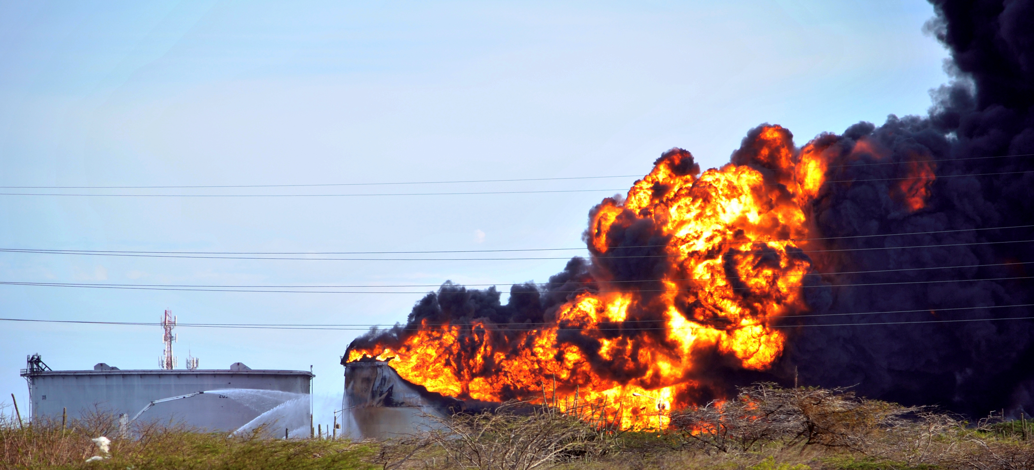Tanque de hidrocarburo siendo enfriado con espuma por cañones de alta presión.