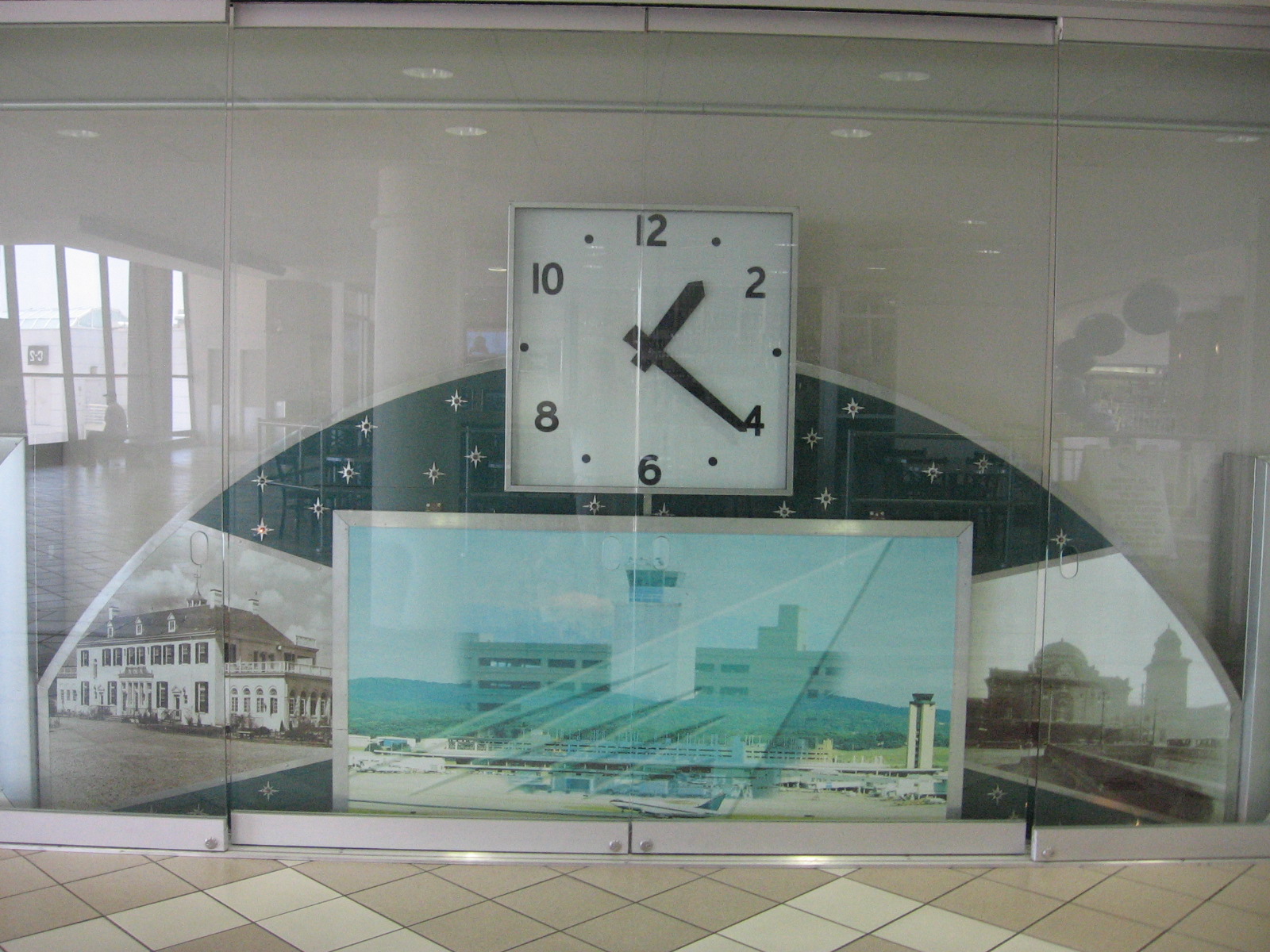 Display in the Birmingham International Airport terminal of the analogue clock with blinking stars which once hung above the main entrance doorway of the 1962 terminal and, with an adjacent sign, welcomed arriving passengers to Birmingham as they exited the terminal. Modified from its original appearance, the clock now includes photos of the current terminal, the 1931 terminal, and Birmingham’s Byzantine style Terminal Station which served the railroads of Birmingham until being demolished in 1969.[11]