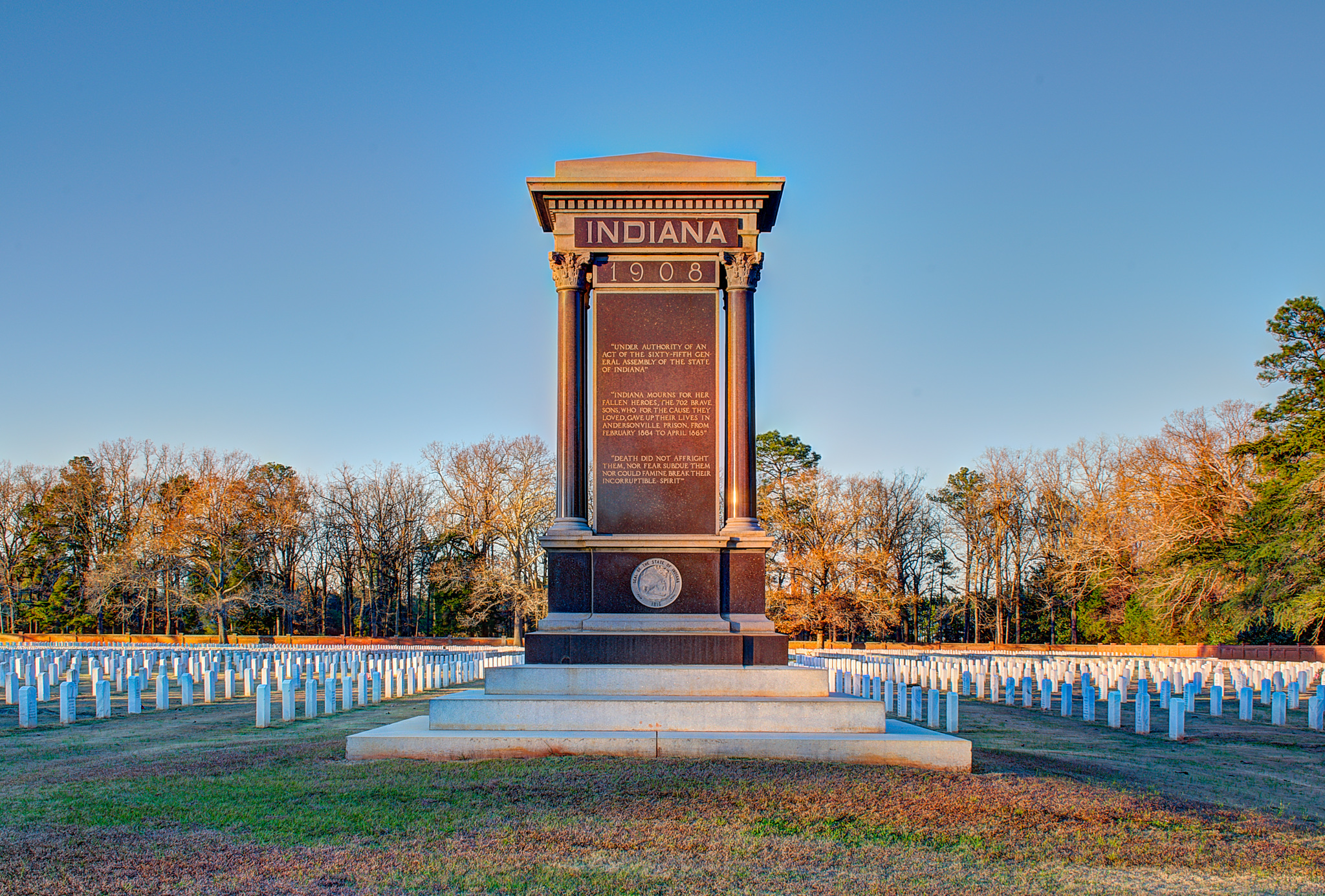 South Side:
Indiana 1908
Under Authority Of An Act Of The Sixty-Fifth General Assembly Of The State Of Indiana.
Indiana Mourns For Her Fallen Heroes, The 702 Brave Sons, Who For The Cause They Loved, Gave Up Their Lives In Andersonville Prison From February, 1864, To April, 1865.
Death Did Not Affright Them, Nor Fear Subdue Them, Nor Could Famine Break Their Incorruptible Spirit.



East Side:
With Great Pity For Their Sufferings, But A Greater Admiration For Their Unfaltering Fidelity.


North Side:
Till The Mountains Are Worn Out, And The Rivers Cease To Flow, Shall Their Names Be Kept Fresh With Reverent Honors, Which Are Inscribed Upon The Book Of National Remembrance.


West Side:
Not Theirs The Matchless Death By Sword Or Shot; Instead The Agony Of Martyrdom