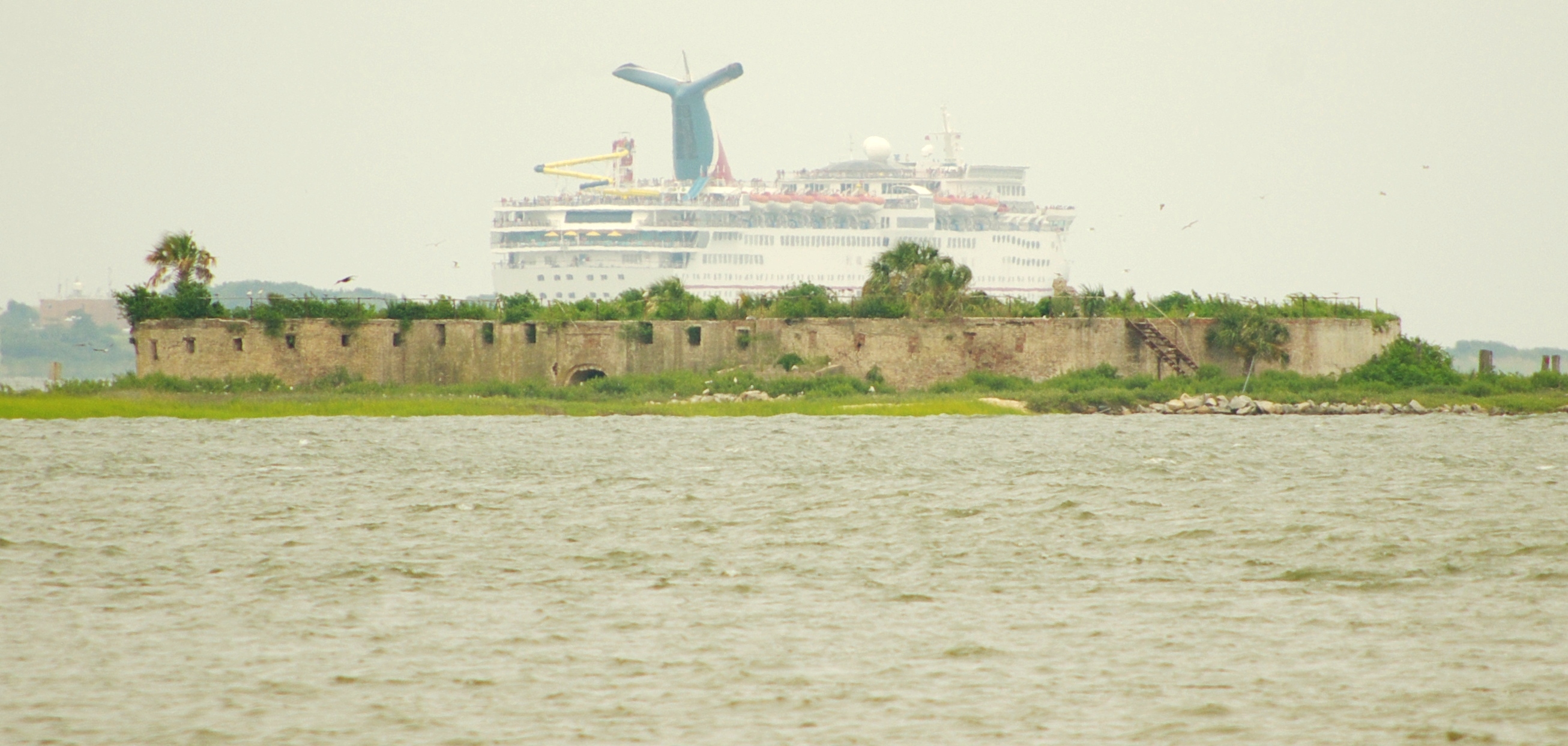 Castle Pinckney on Shutes' Folly Island in Charleston Harbor, with a cruise ship passing in the background.