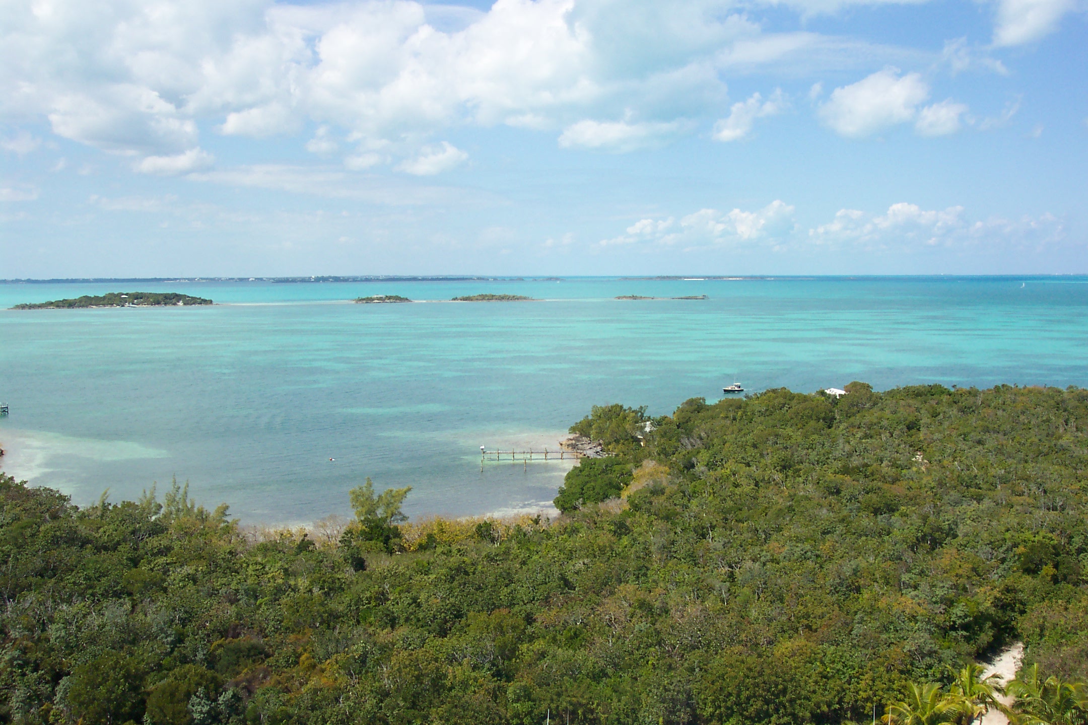 View facing west from the Hope Town Lighthouse on Elbow Cay in the Abaco Islands, Bahamas.  All but one of the Parrot Cays are seen in the turquoise Sea of Abaco, with the eastern shore of Great Abaco Island visible along the horizon.

Note: The above description is by the uploader, Lithium6ion, and has not been endorsed by the author.