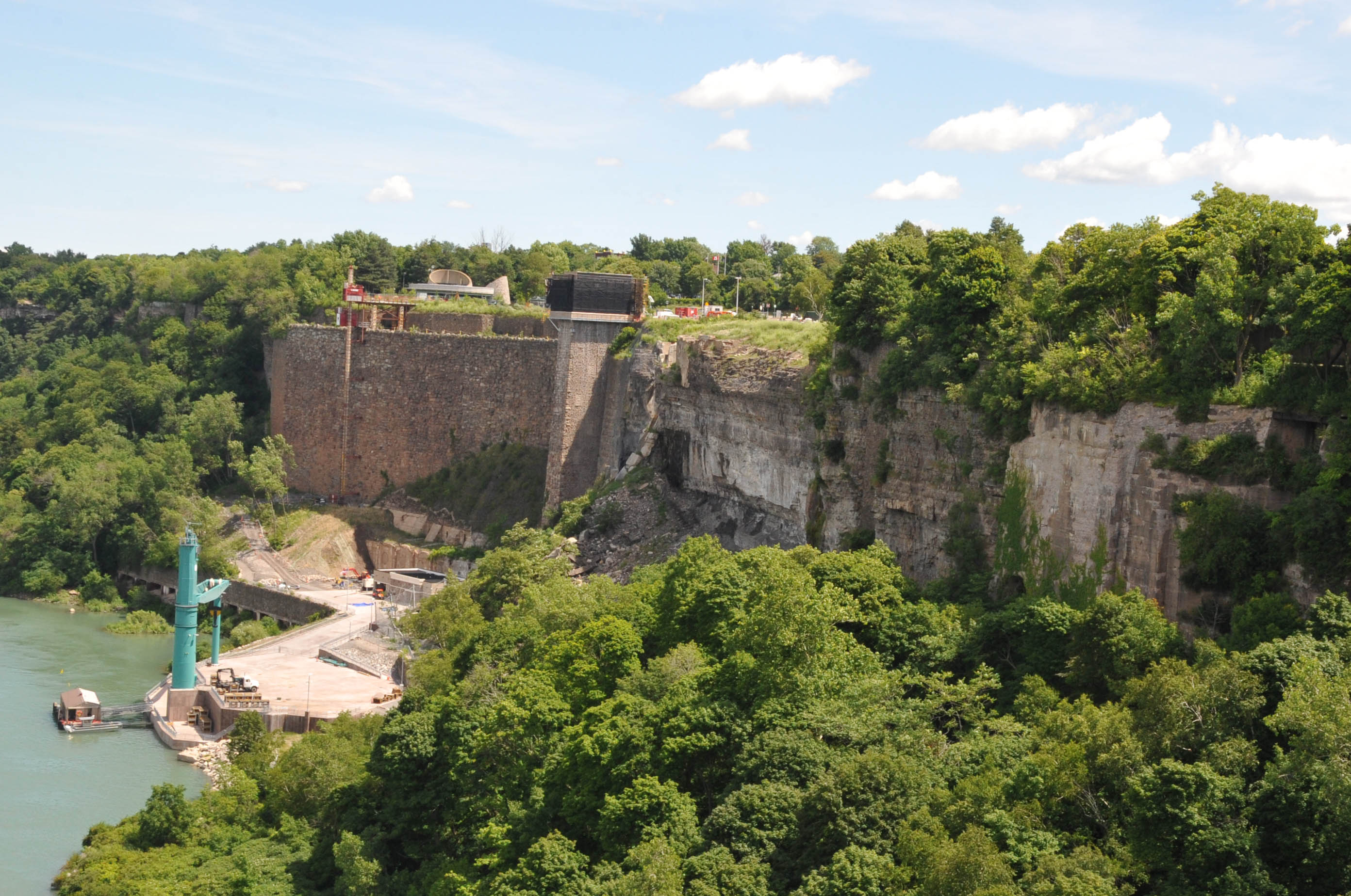 VIEW OF THE SCHOELLKOPF POWER STATION NO 3 SITE FROM THE MIDDLE OF RAINBOW BRIDGE;  IN JUNE OF 1956 WATER SEEPED BEHIND THE POWER STATION AND THE WALL OF NIAGARA GORGE CAUSING 2 OF THE 3 STATIONS TO COLLAPSE INTO THE GORGE,   THIS CAUSED LOSS OF 450,000 KILOWATTS OF POWER TO THE NEW YORK STATE POWER GRID.  IT ALSO LED TO THE GOVERNMENT TAKING OVER THE POWER STATIONS AND THE END OF PRIVATE OWNERSHIP.  TODAY THEY ARE DEVELOPING THE SITE BY RE-INSTALLING THE ELEVATOR TO THE BOTTOM AND OPEN THE SITE TO TOURISTS.  THE WALL BEHIND 1 POWER PLANT IS STILL INTACT AND DEBRIS FROM THE OTHER TWO IS STILL SEEN AT THE BOTTOM OF THE GORGE.