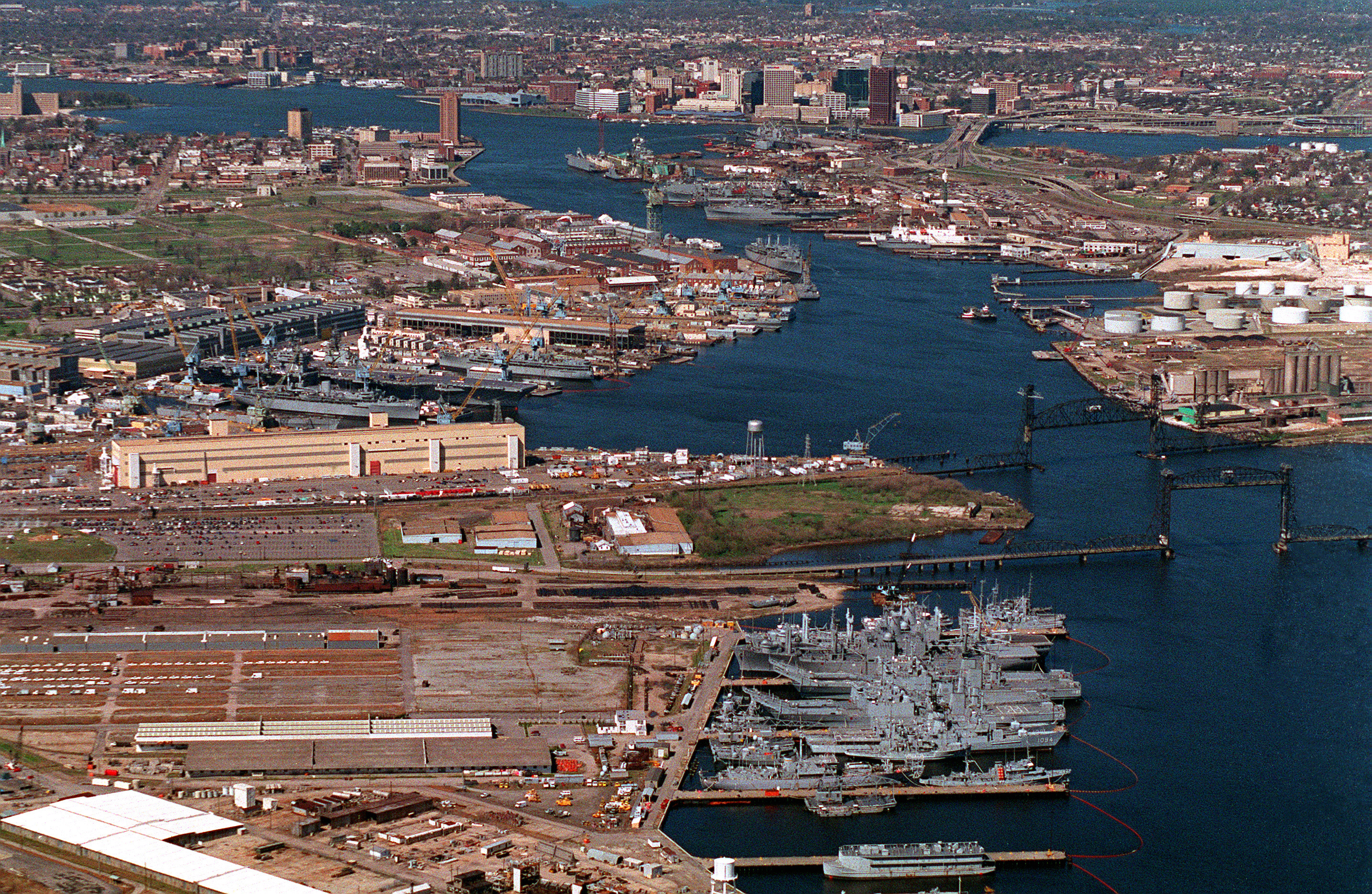 An aerial view of the U.S. Navy Norfolk Naval Shipyard located on the Elizabeth River, Virginia (USA), in 1995. At the bottom right is the South Gate Annex where ships of the mothball fleet are stored. At left center is the main shipyard. Futher back on the righthand side of the river is the Norfolk Shipbuilding &amp; Drydock Company (NORSHIPCO). The city of Norfolk is in the background.