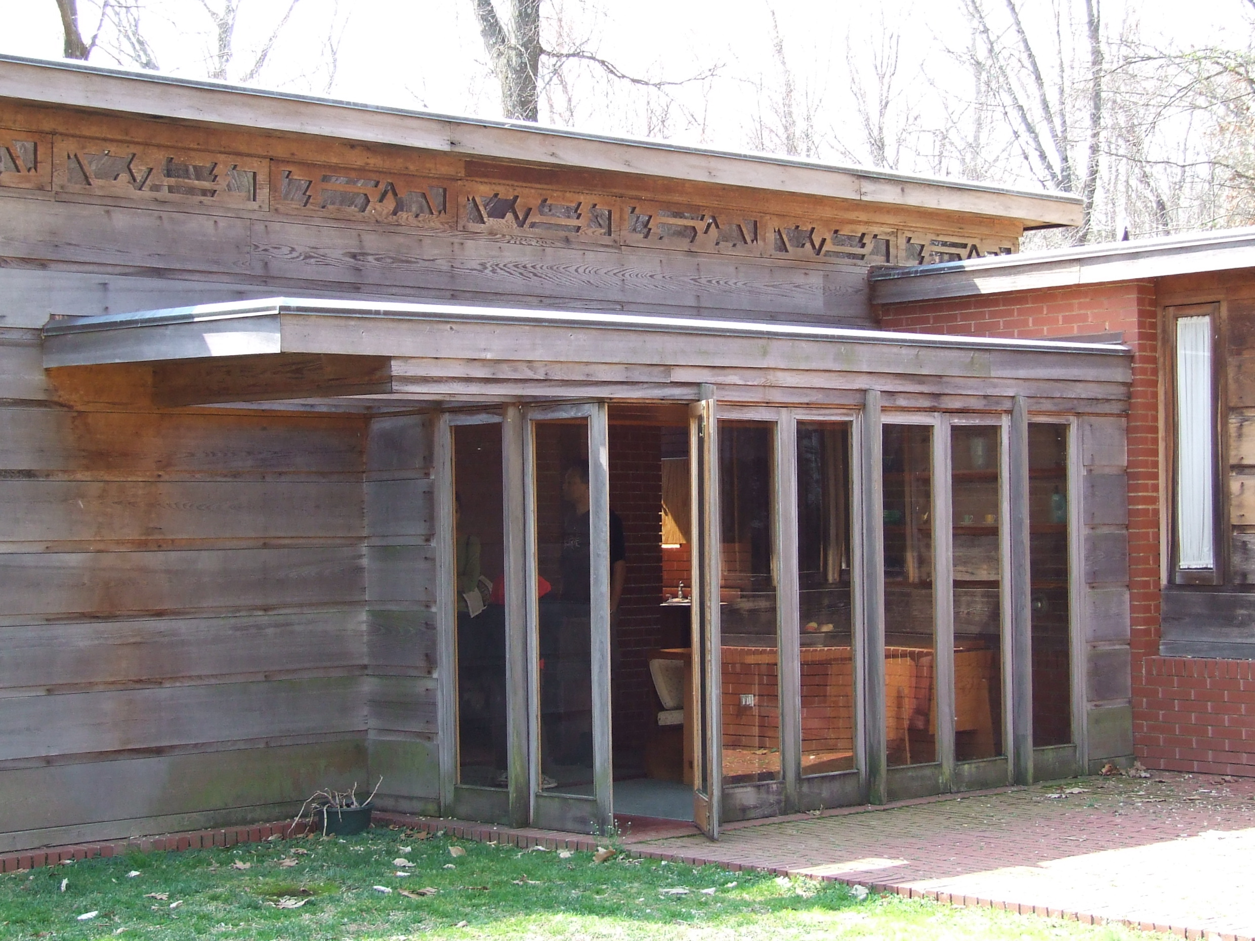Exterior of Pope-Leighey House, with dining room visible through full-length windows.