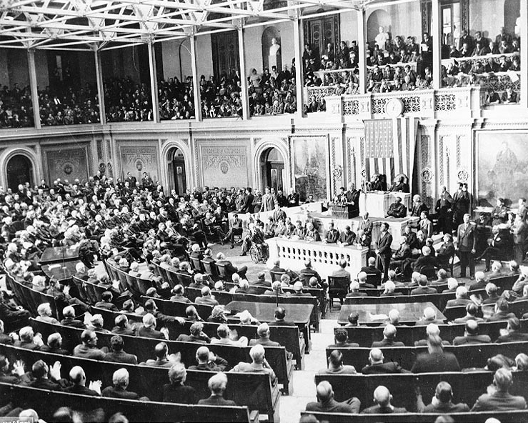 U.S. President Franklin Delano Roosevelt addresses a joint session of United States Congress.
It is typically identified as a photo of Roosevelt's "Infamy" speech, December 8, 1941, however this has been disputed. It is also possible that this photo was actually taken during his "Four Freedoms" speech (State of the Union address, January 6, 1941) or his 1942 State of the Union address (January 6, 1942). Photo 208-CN-3992