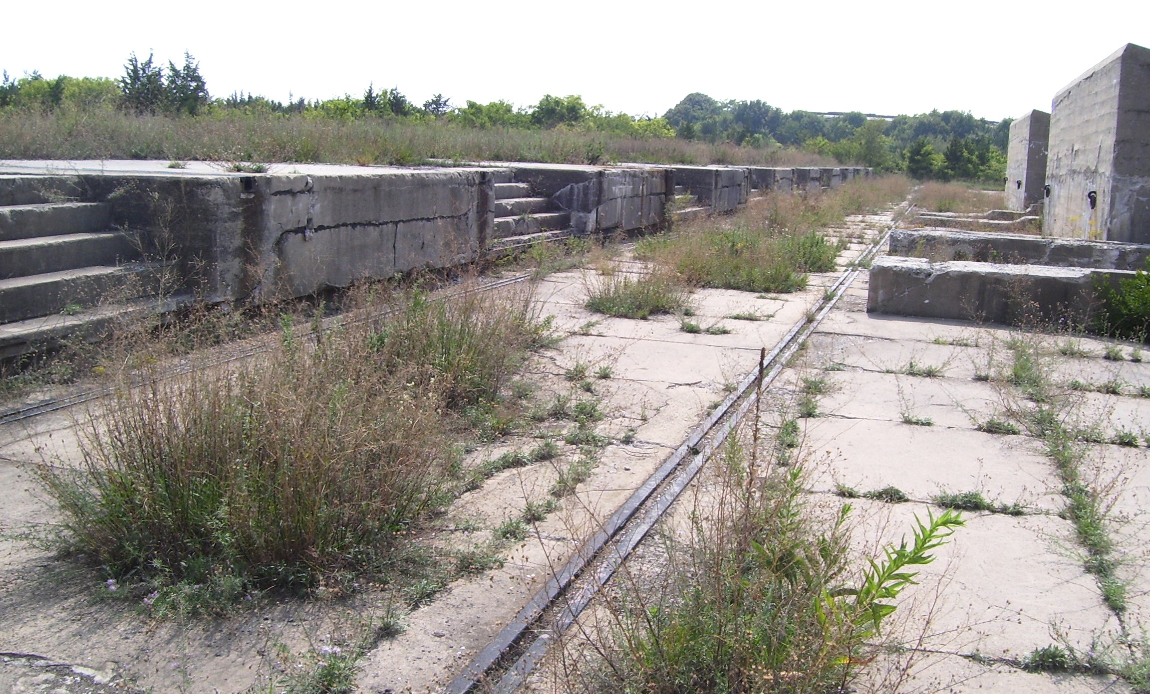 Abandoned concrete gun platforms, formerly part of the Proof Battery of the Sandy Hook Proving Ground, in use from 1901-1919. To the right are protective walls, or "traverses".  Soldiers used a 20-foot gantry crane on rails to lift guns and carriages onto the platforms to be tested, or "proved".  Sandy Hook is now part of the Gateway National Recreation Area; these platforms are near North Beach.