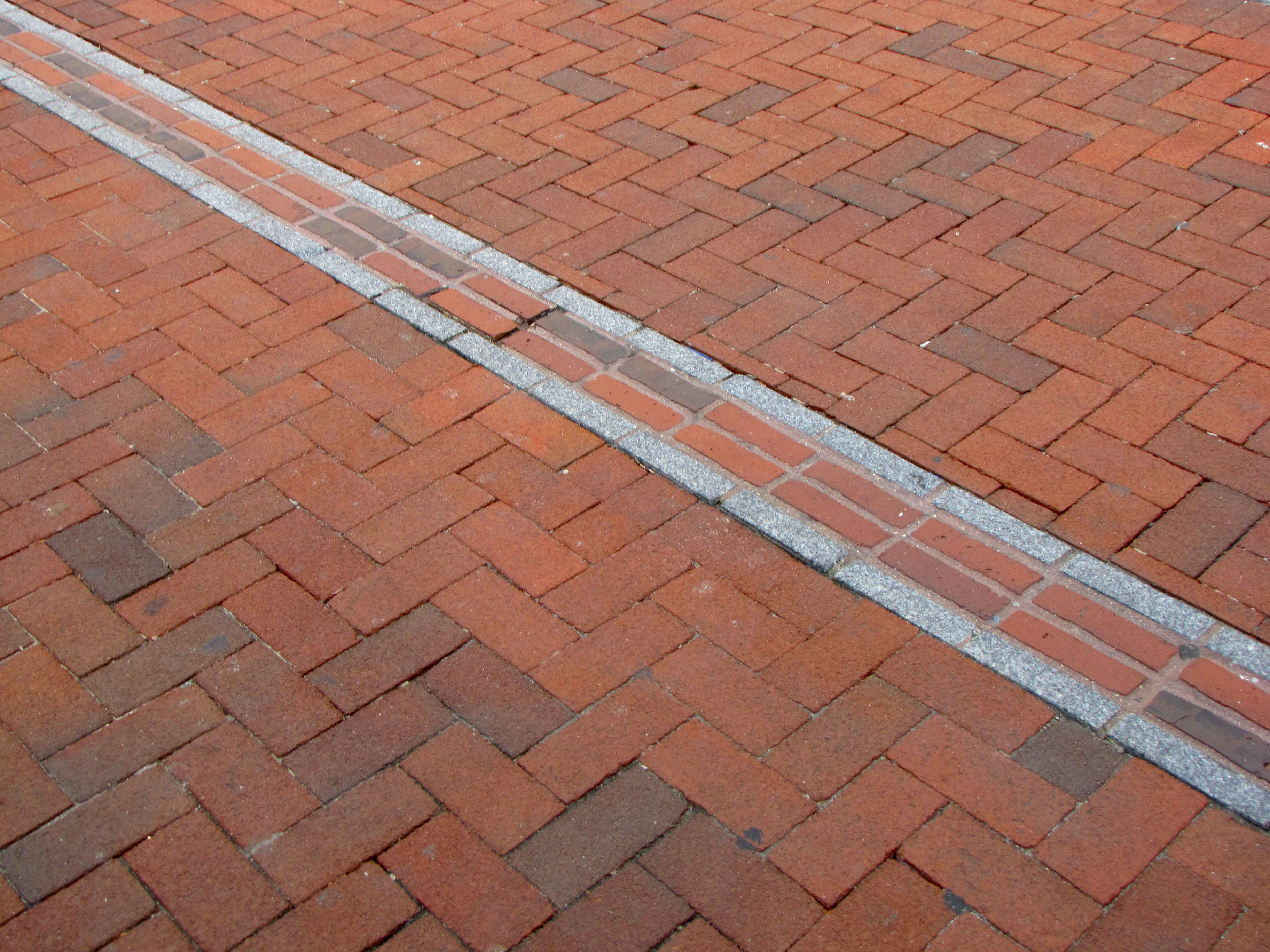 Freedom Trail path on a red brick sidewalk in downtown Boston, Massachusetts.