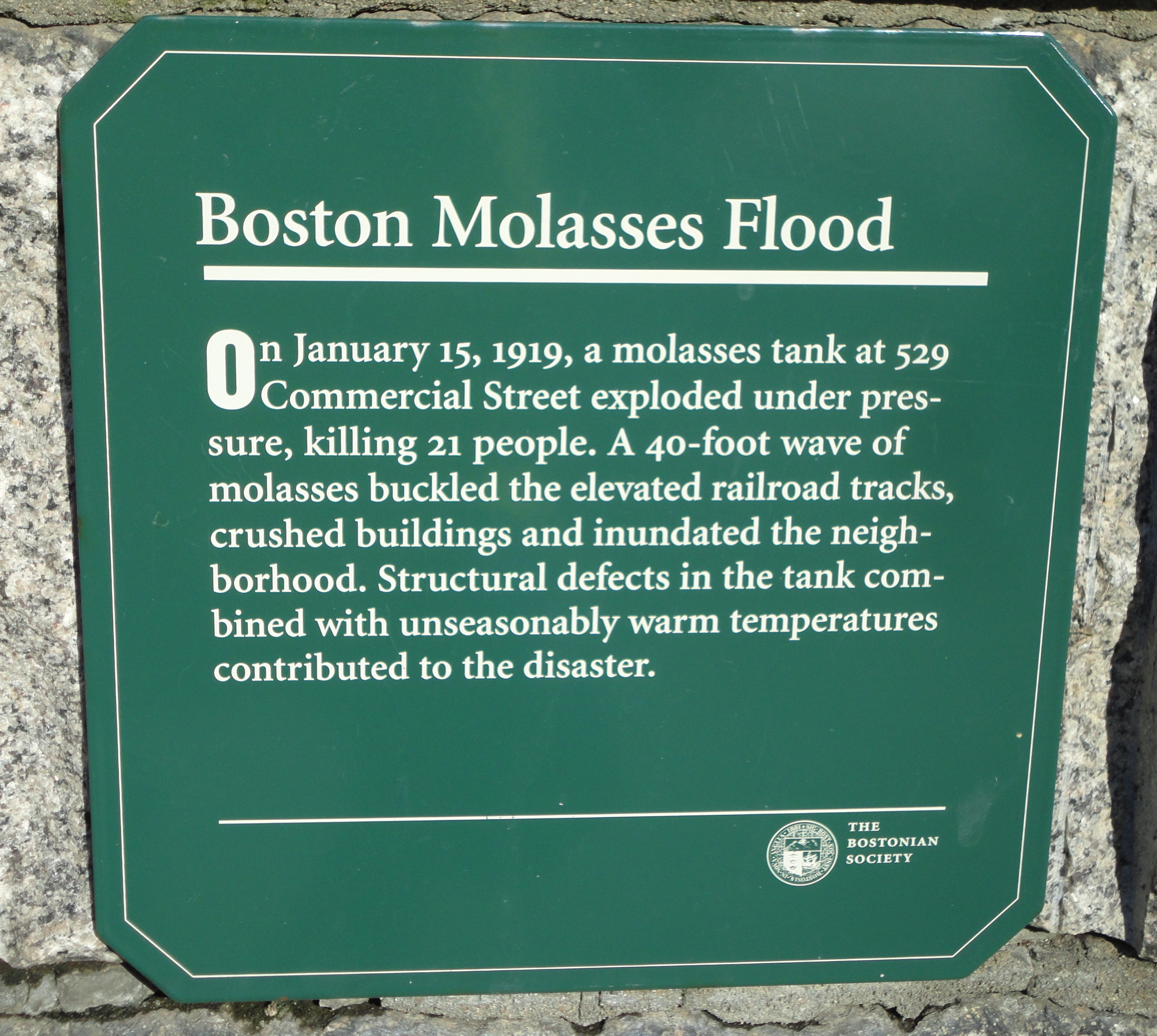 Erected by the Bostonian Society near the site of the Great Molasses Flood of 1919. It reads, "On January 15, 1919, a molasses tank at 529 Commercial Street exploded under pressure, killing 21 people. A 40-foot wave of molasses buckled the elevated railroad tracks, crushed buildings and inundated the neighborhood. Structural defects in the tank combined with unseasonably warm temperatures contributed to the disaster."