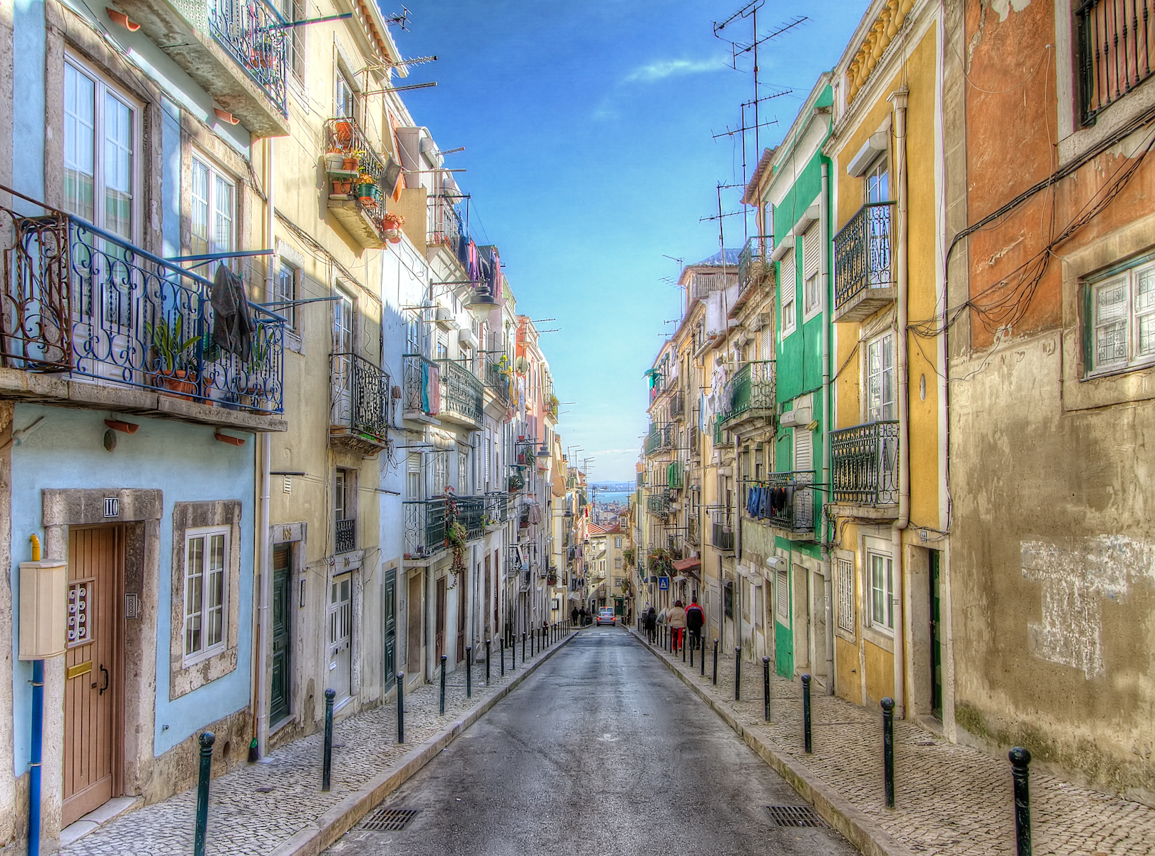 There are lots of beautiful narrow streets in Lisbon and you can spend the whole day walking up and down.
This is an HDR of three handheld shots. There is a lot of contrast in the afternoon because the sun only falls on the top of the buildings. I made the end result look closest to the +2 shot, using the darker exposures to get the sky and the tops of the buildings. Used OnOne Perfect Effects to add a slight texture, most visible in the sky.